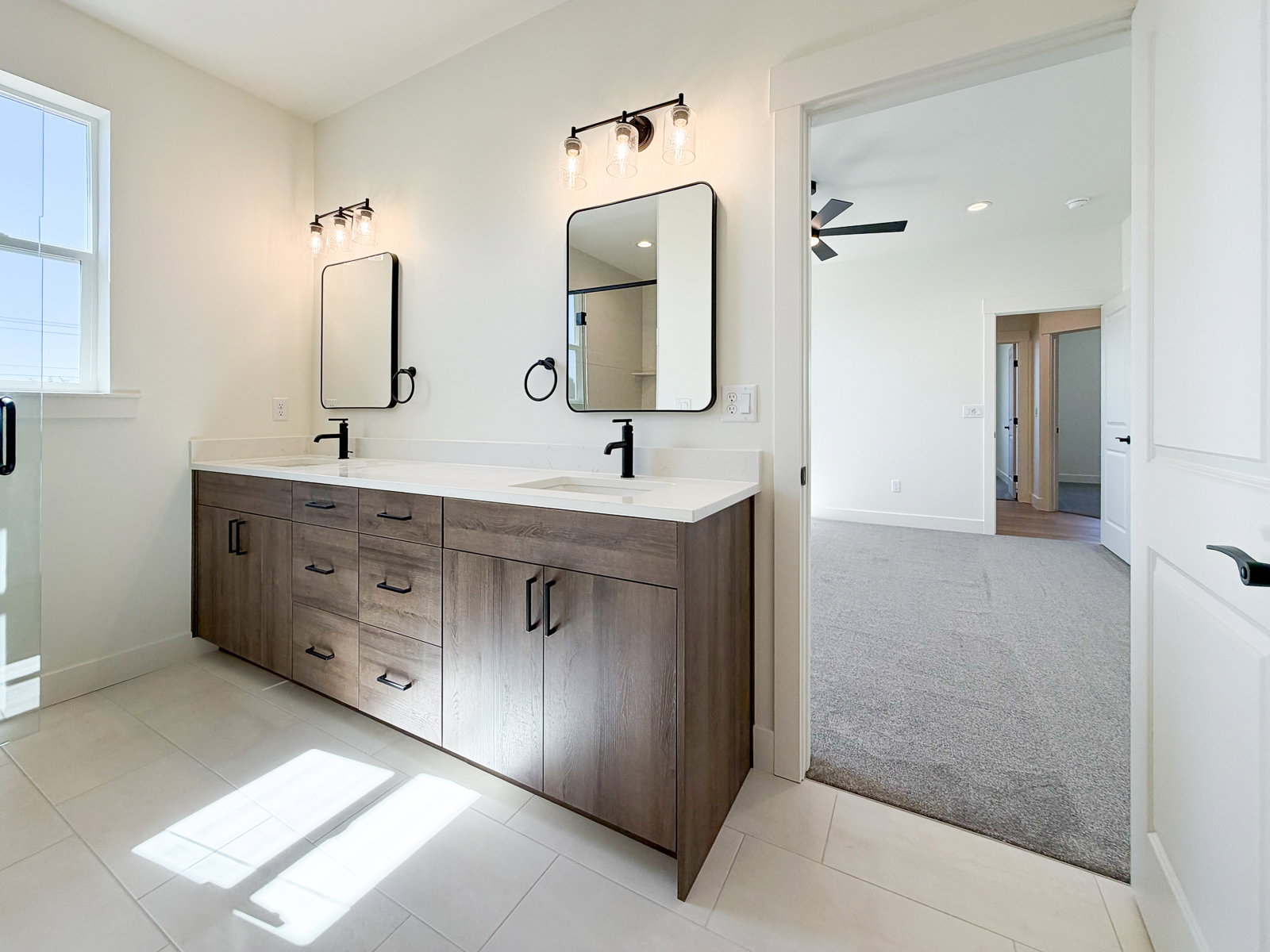 Bathroom featuring a double vanity with wood-finish cabinetry, white countertops, and black fixtures