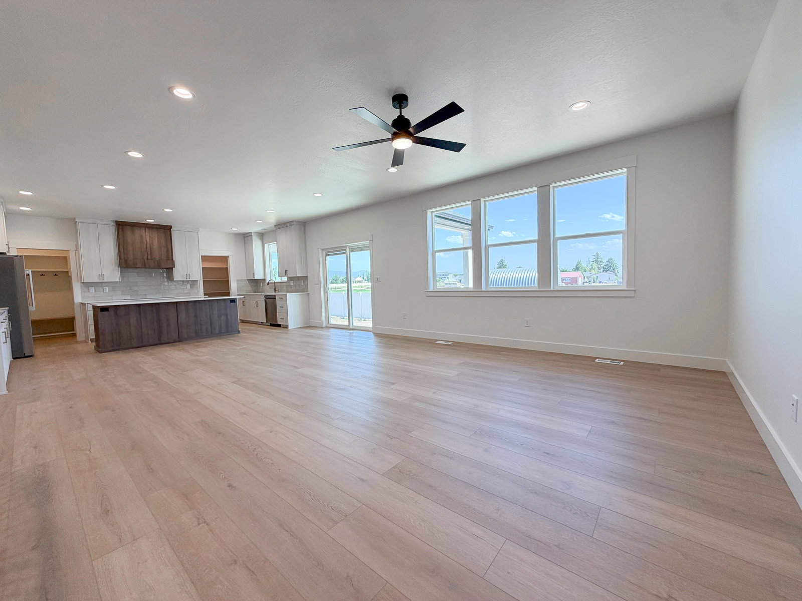 Open-concept living area with wood-finish flooring, recessed lighting, and a ceiling fan