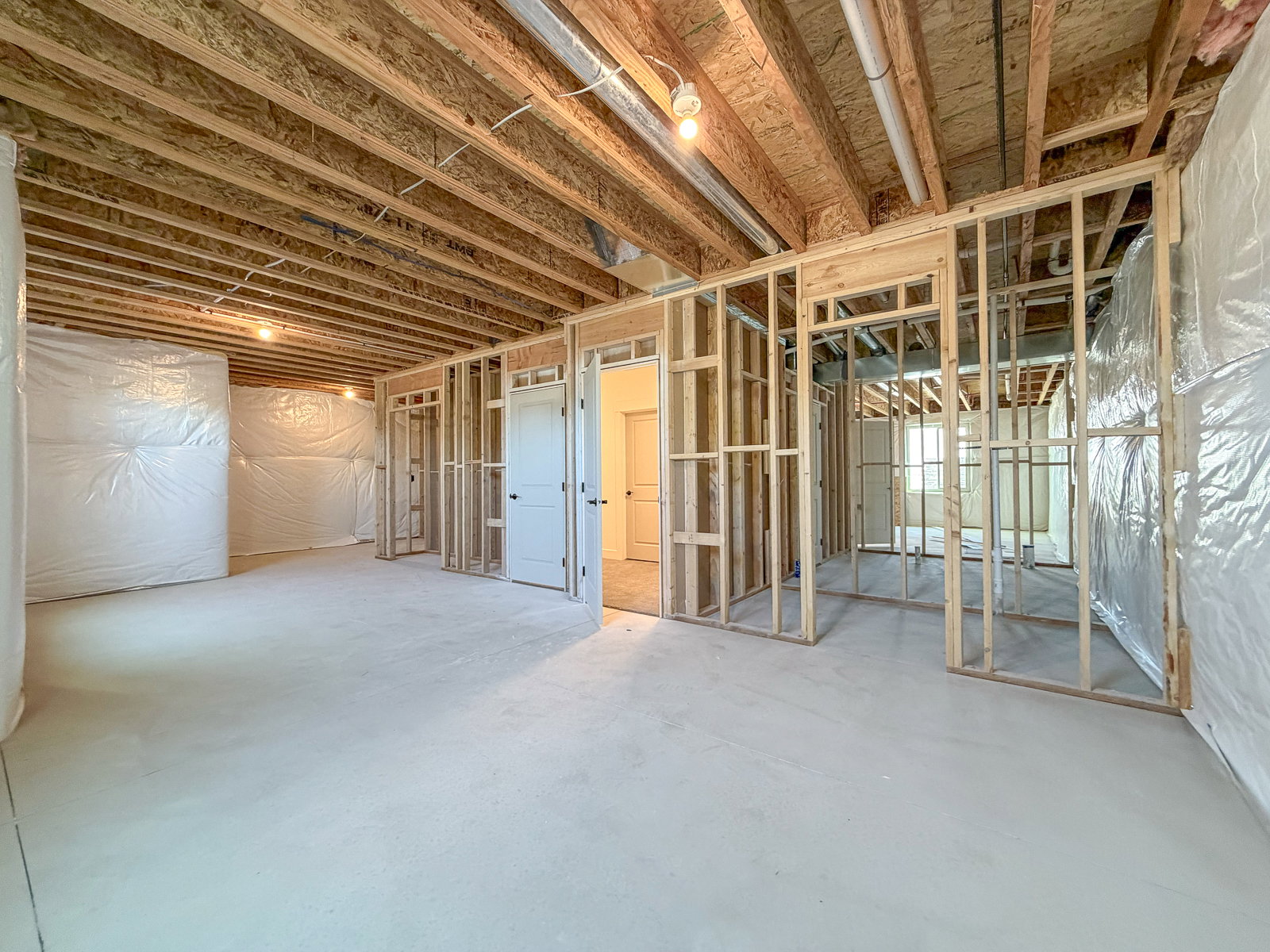 Unfinished basement featuring exposed wood joists, framed interior walls, and a concrete floor