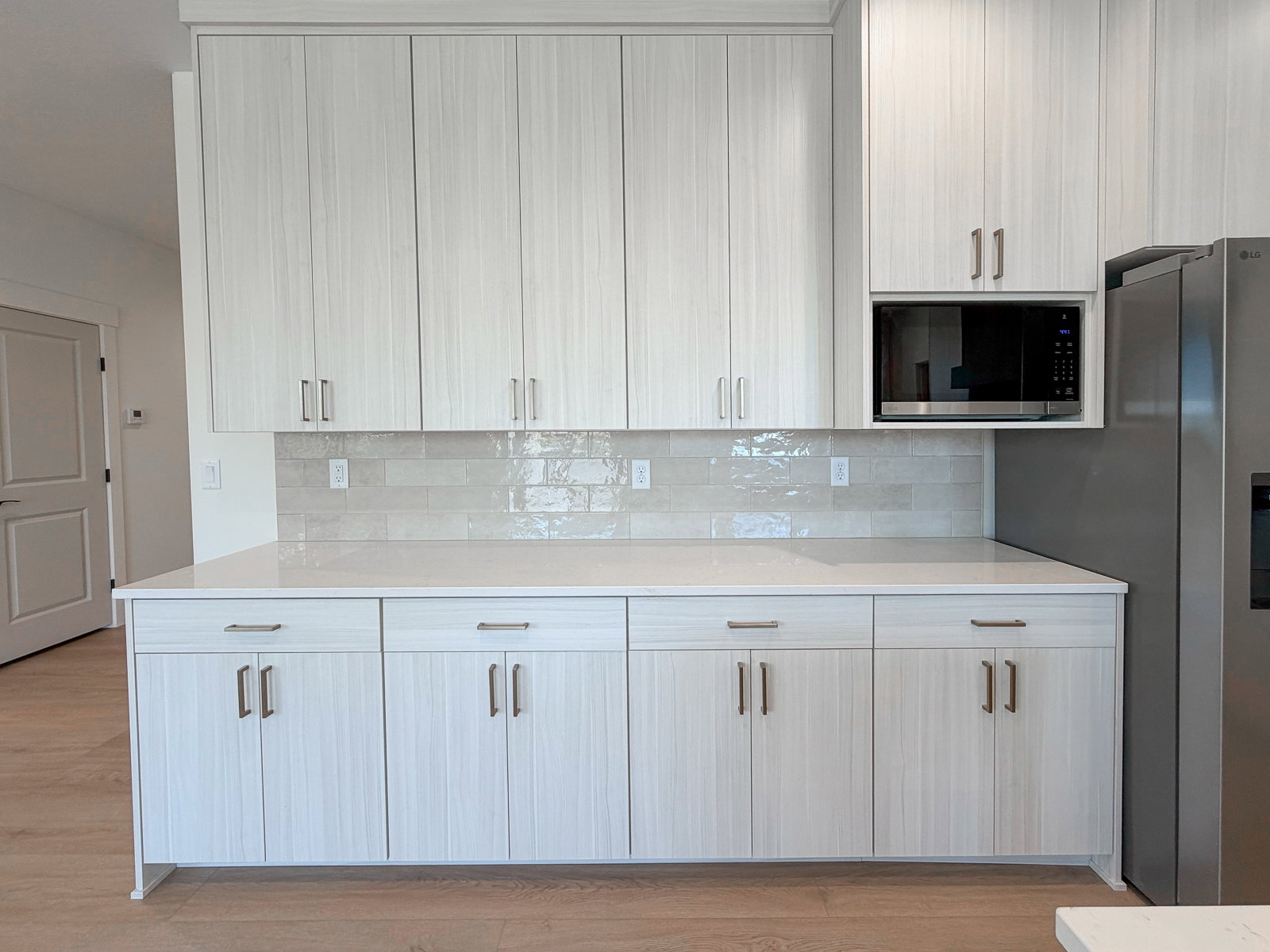 Kitchen featuring extensive light wood-finish cabinetry, light-toned countertops, a light subway tile backsplash, and stainless steel appliances