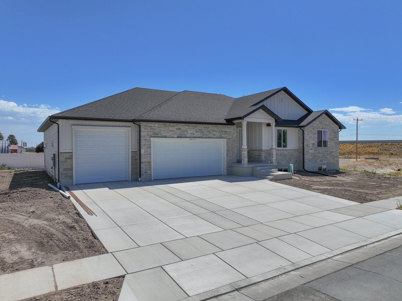 Contemporary ranch-style home featuring a two-car garage, stone and siding exterior, a covered porch, and a concrete driveway