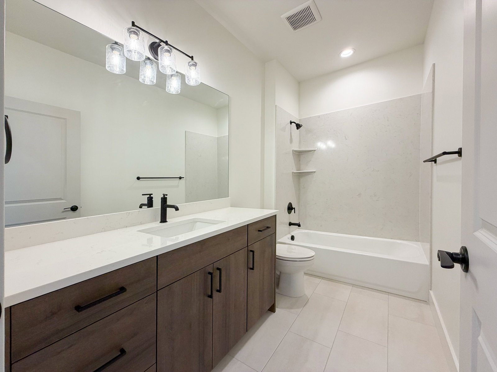 Contemporary bathroom featuring a wood-finish vanity with ample storage, a white countertop, and a rectangular undermount sink