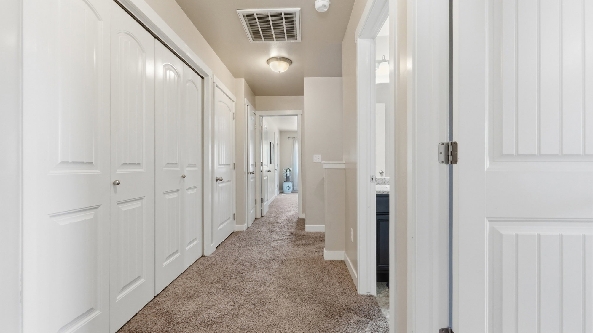 Hallway with neutral tone carpeting and light-colored walls