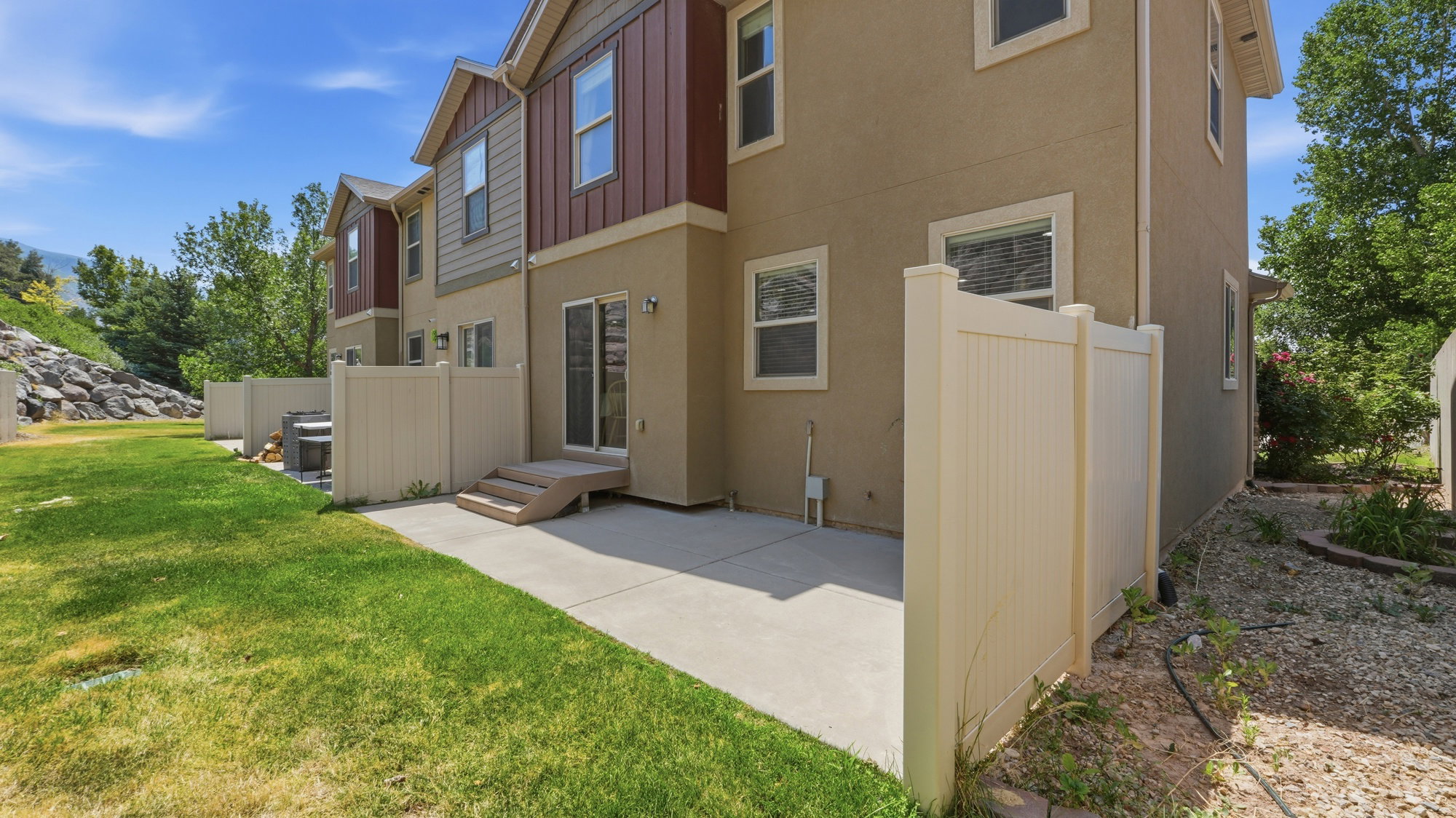 Rear exterior featuring a concrete patio, sliding glass door access, and multi-tone siding