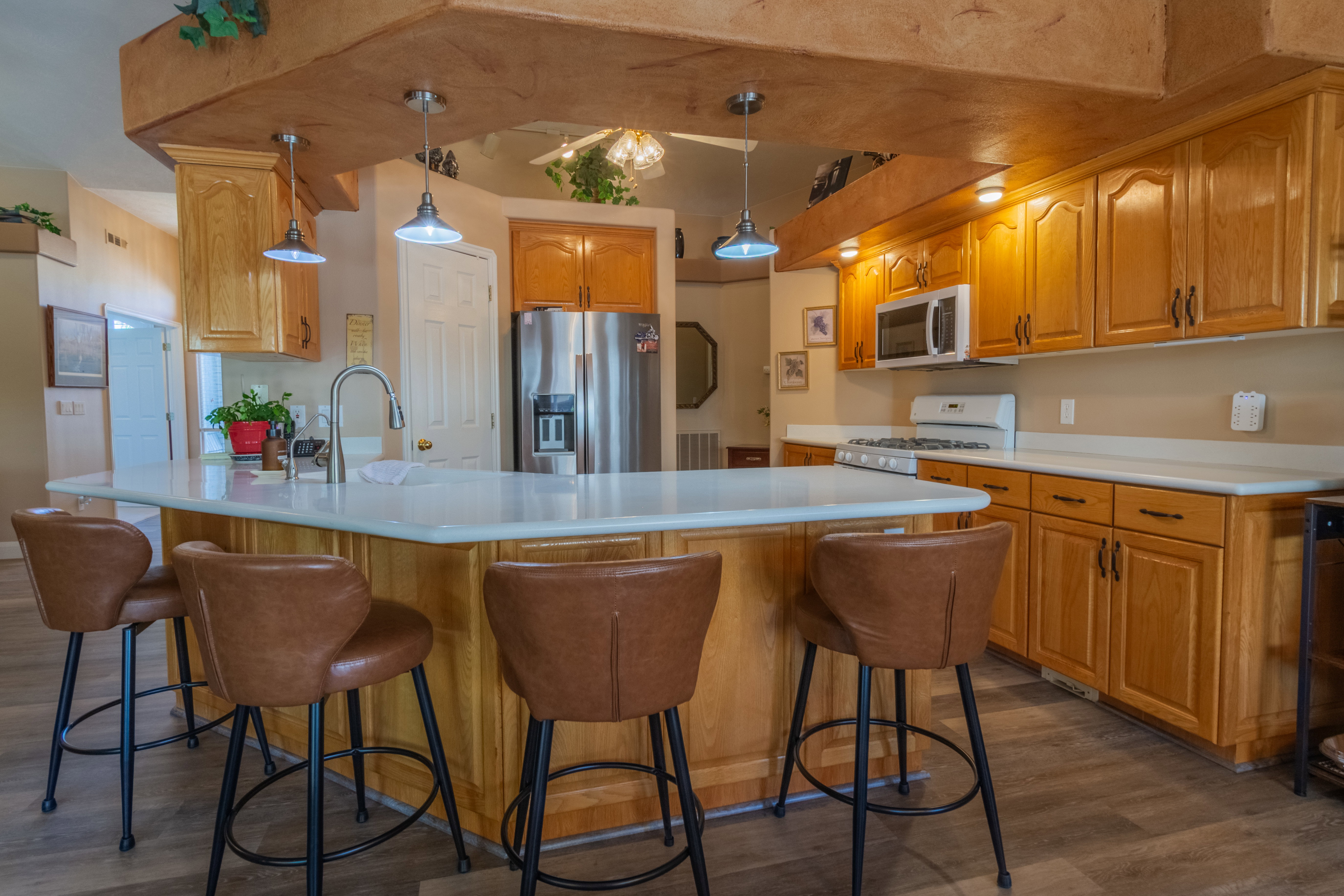 Kitchen featuring an island with a white countertop, light wood cabinetry, stainless steel appliances, a gas range, and wood-finish flooring