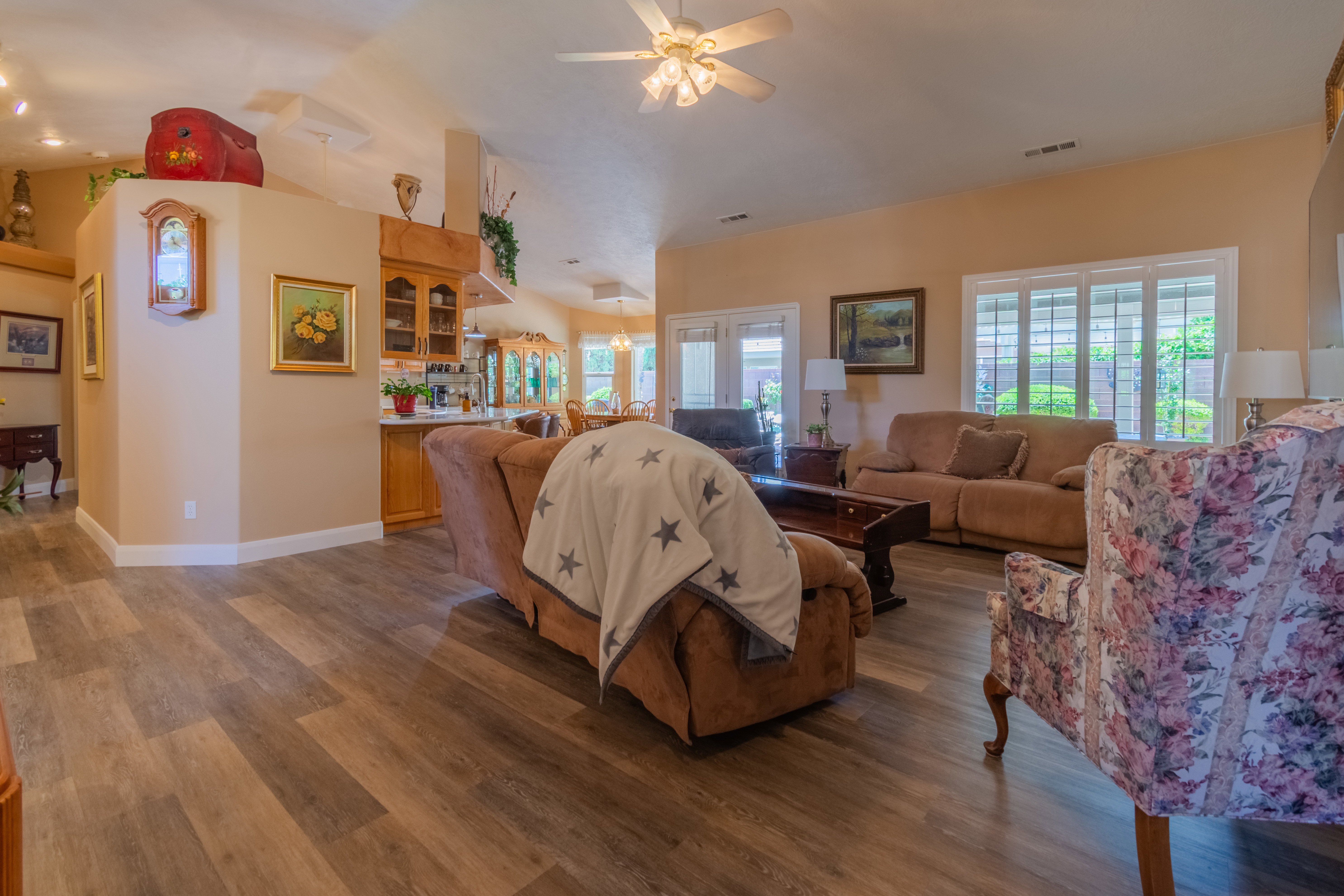 Spacious living area featuring wood-finish flooring, vaulted ceilings, and a ceiling fan