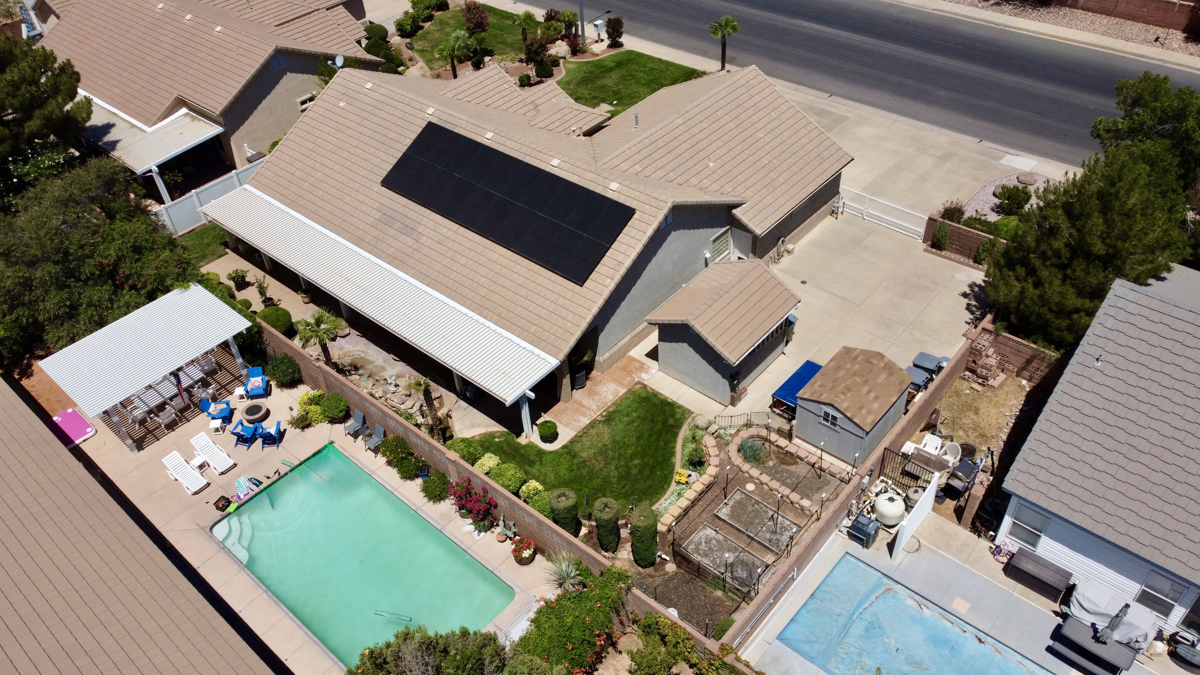Rear exterior featuring a rectangular in-ground pool, covered patio, and a separate shaded pergola area