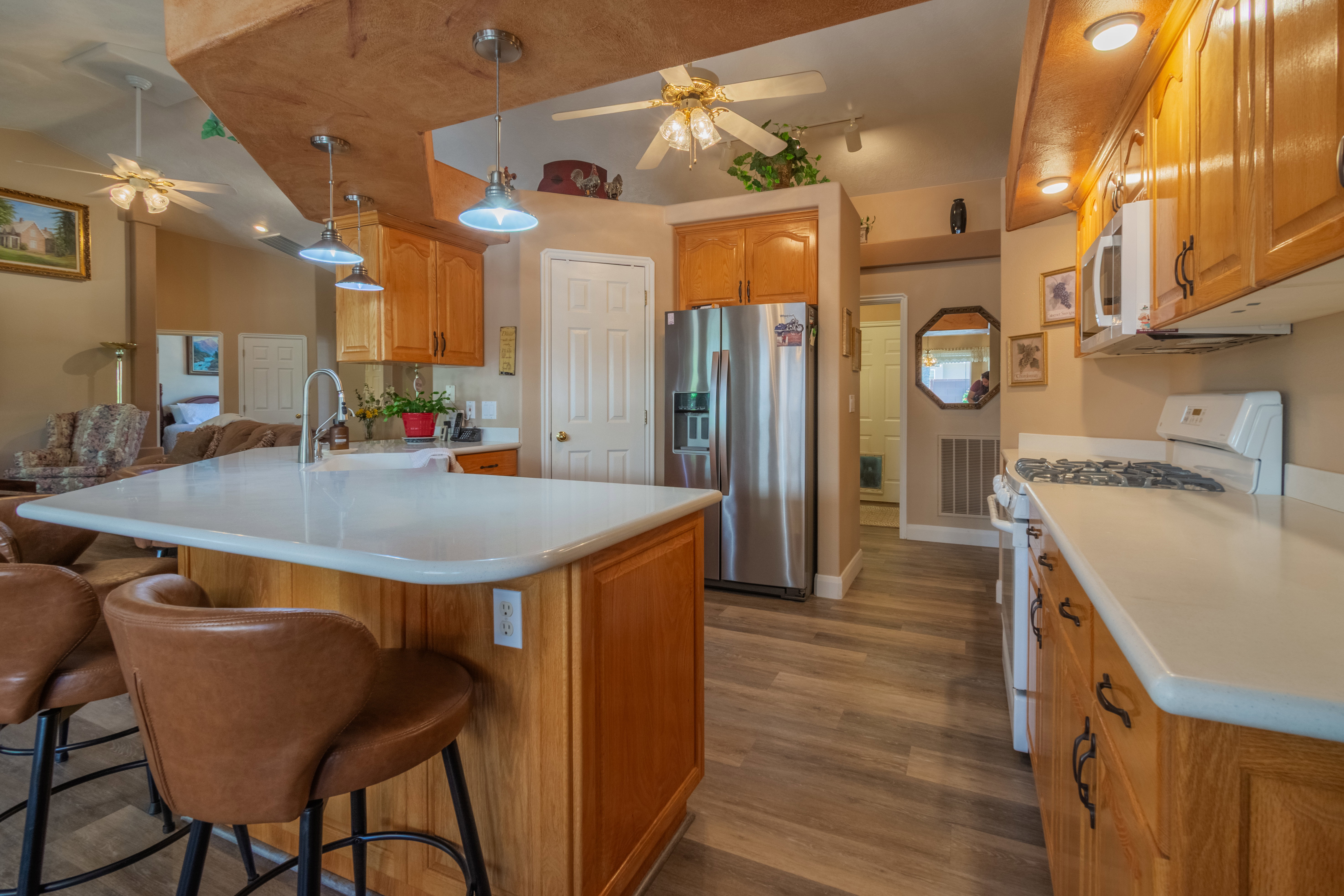 Kitchen featuring a central island with countertop seating, wood-finish cabinetry, stainless steel refrigerator, white gas range, and wood-finish flooring