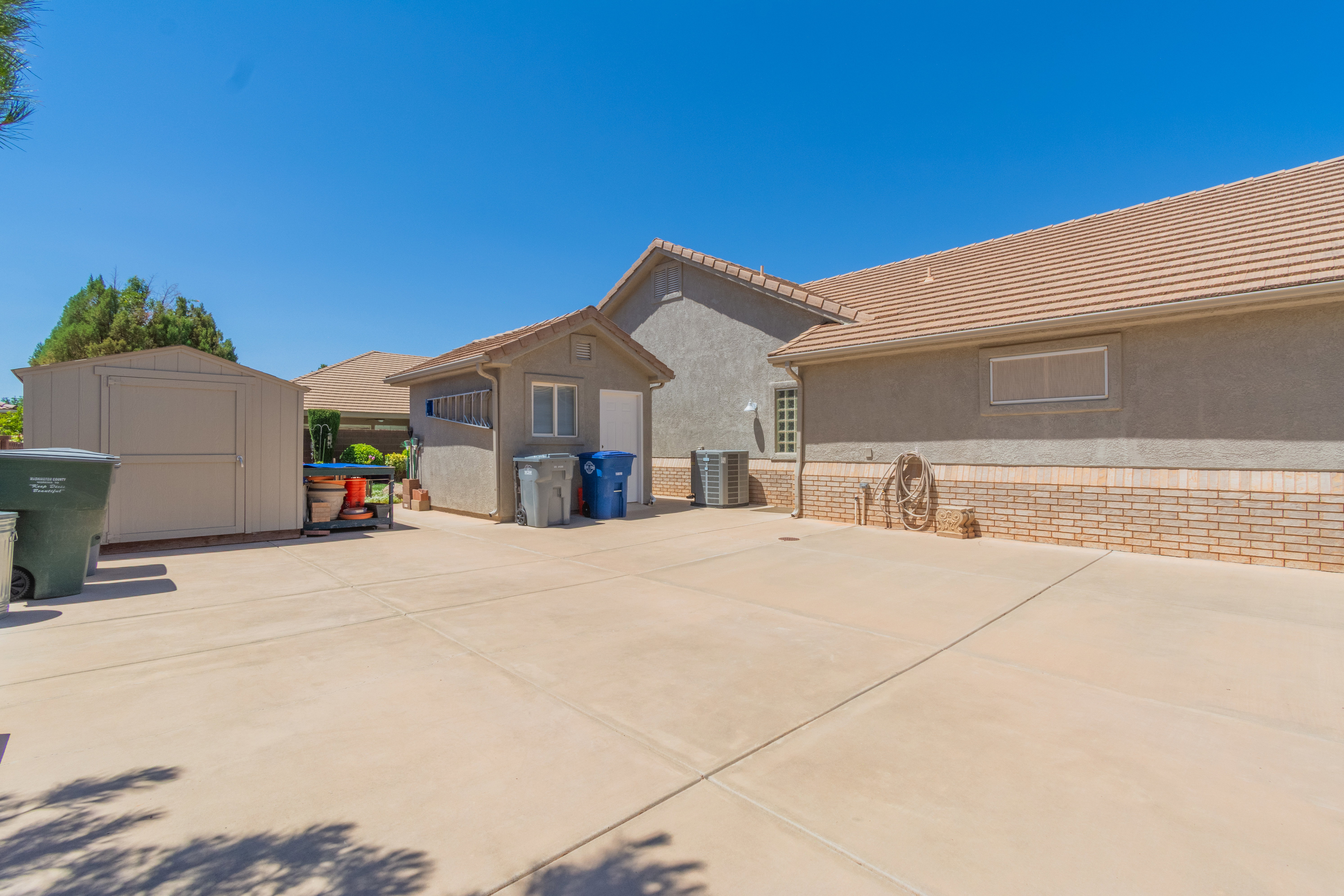 Expansive concrete driveway with a large freestanding storage shed and an additional detached utility structure