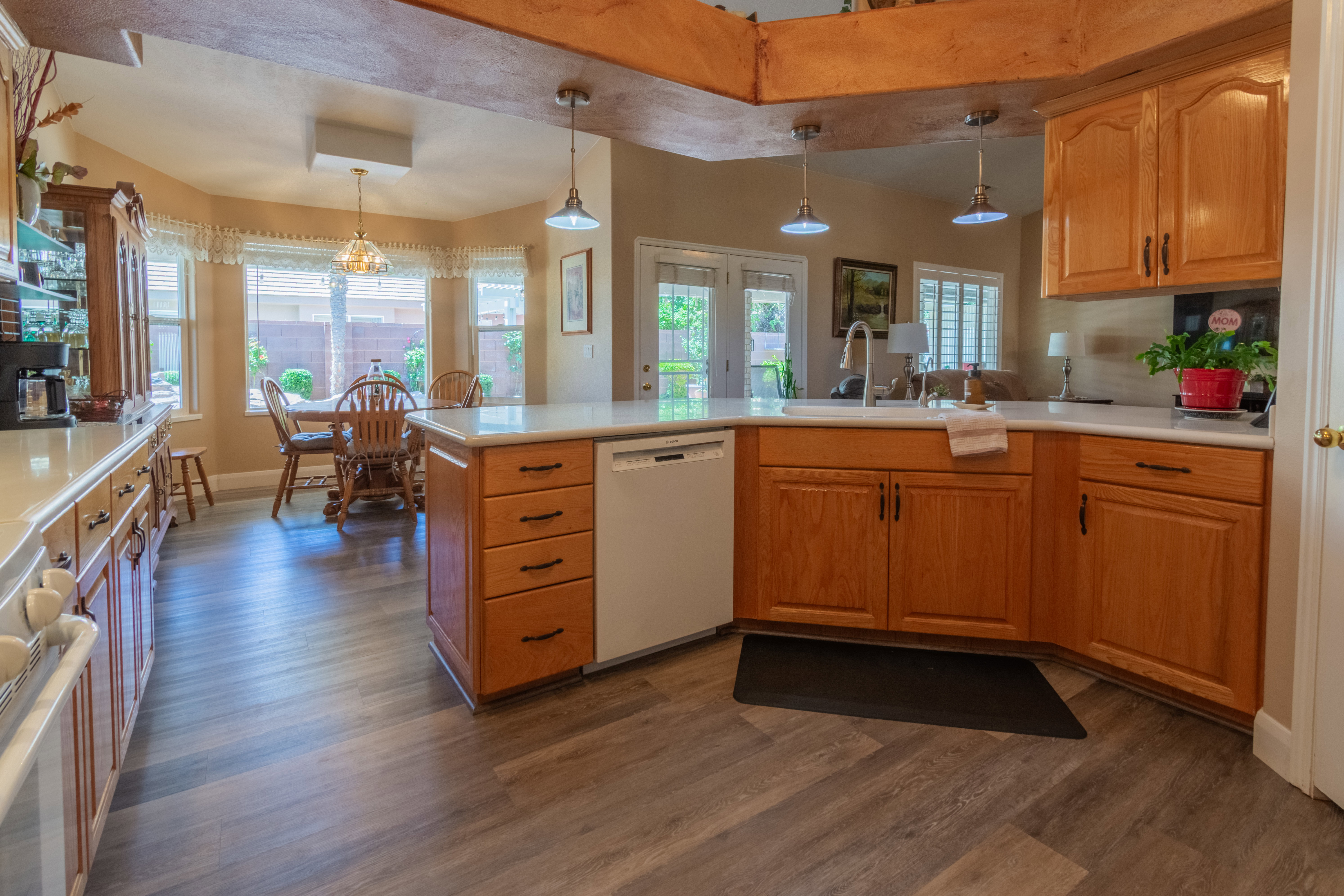 Kitchen featuring wood-finish flooring, light wood cabinetry, light-toned countertops, and a built-in dishwasher