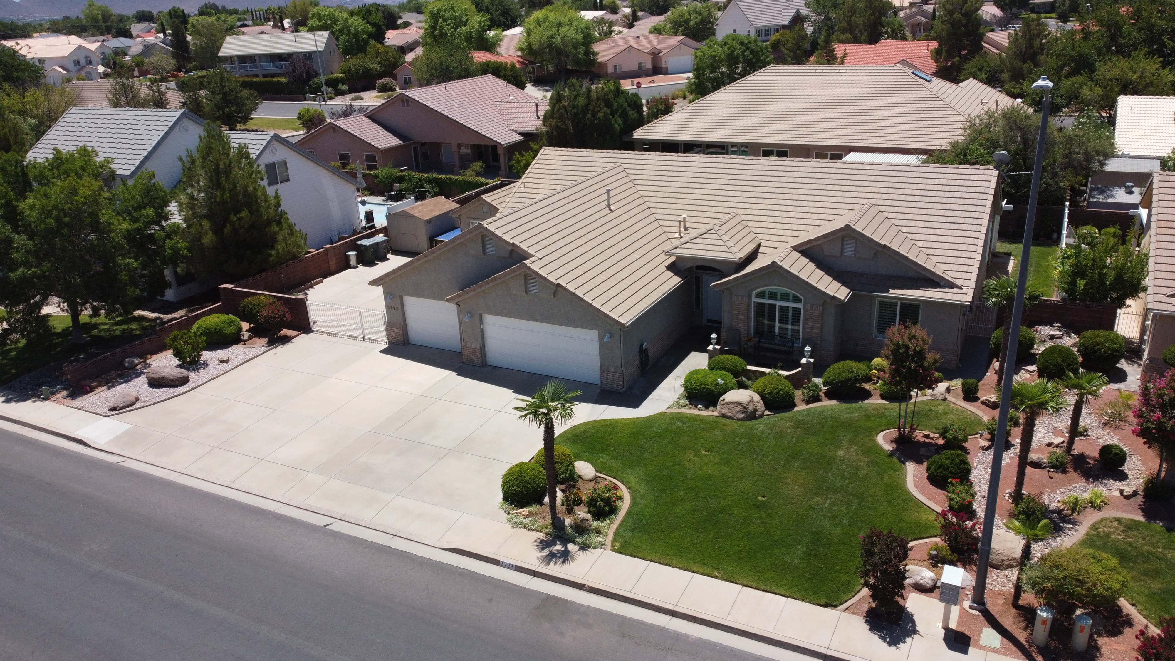 Spacious residence featuring a two-car garage, mature landscaping, a tiled roof, and a generously sized concrete driveway