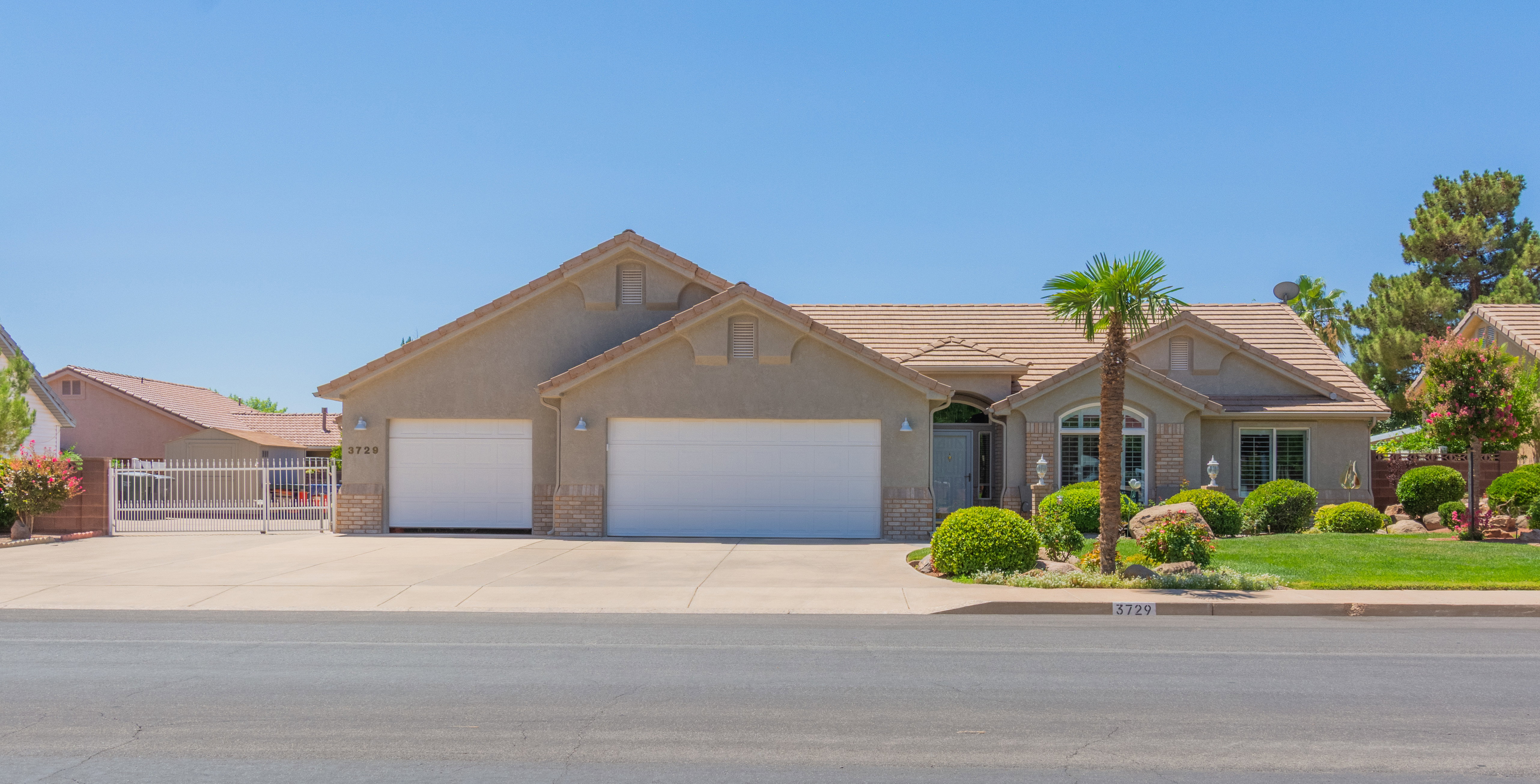Stucco exterior residence featuring a tile roof, an arched front window, and a two-car garage