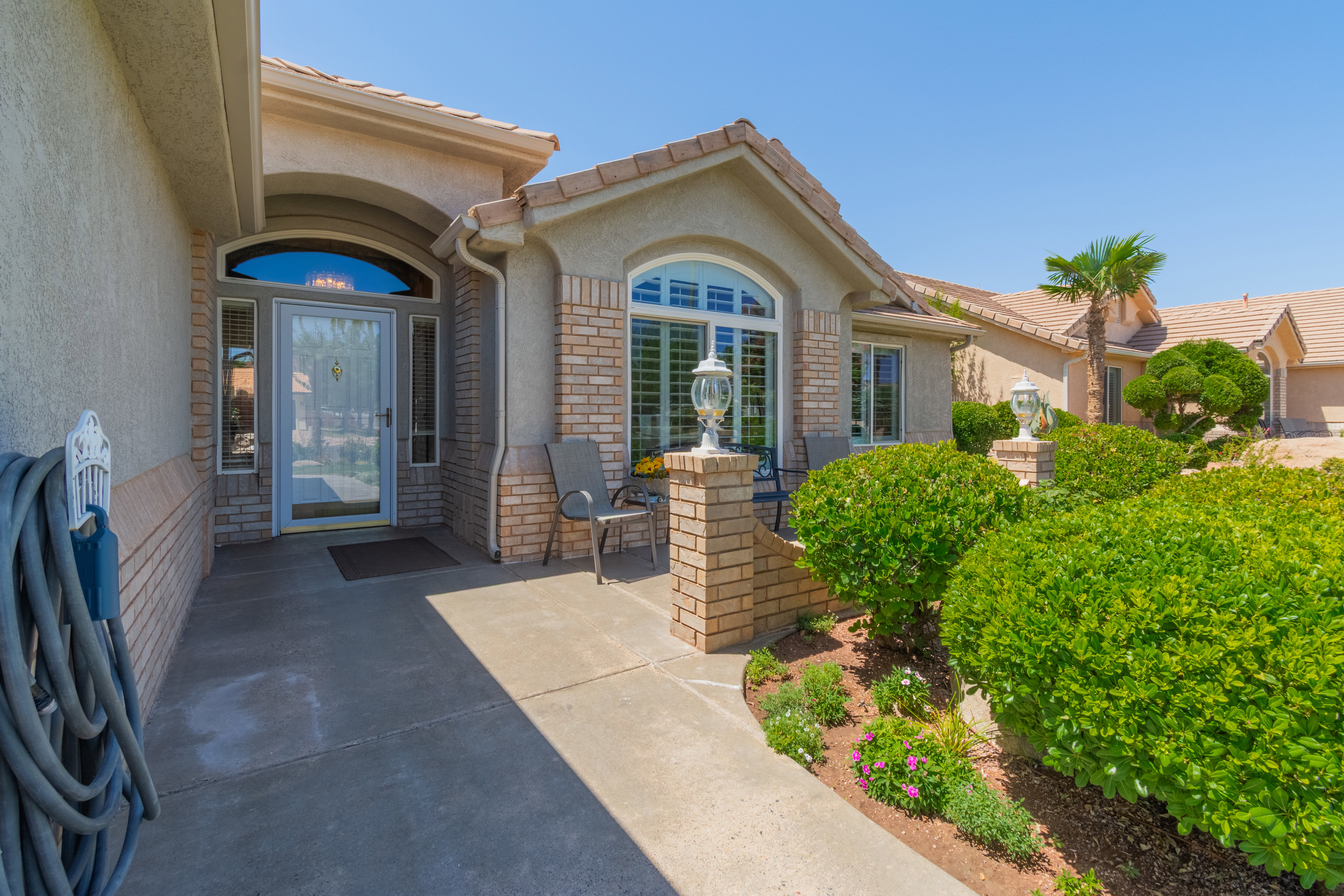Entryway featuring a full-light door with sidelights and an arched transom window, a brick facade, stucco exterior, and concrete pathway