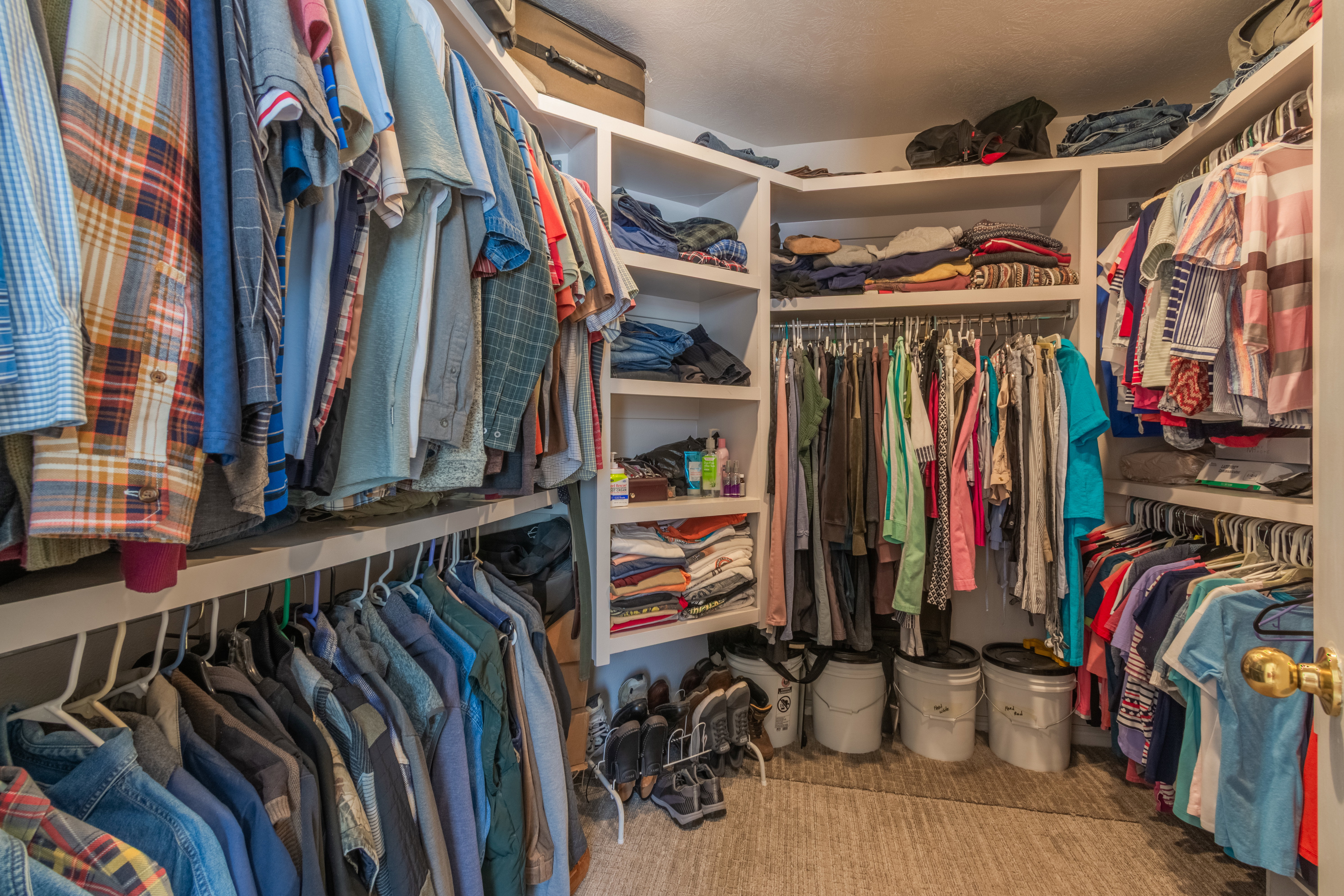 Walk-in closet featuring extensive built-in shelving and multiple hanging rods for comprehensive storage