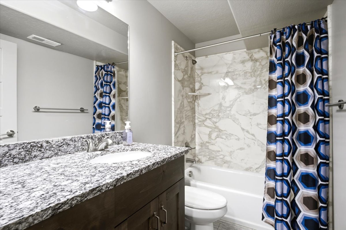 Bathroom vanity with a granite countertop, integrated sink, and dark wood cabinetry