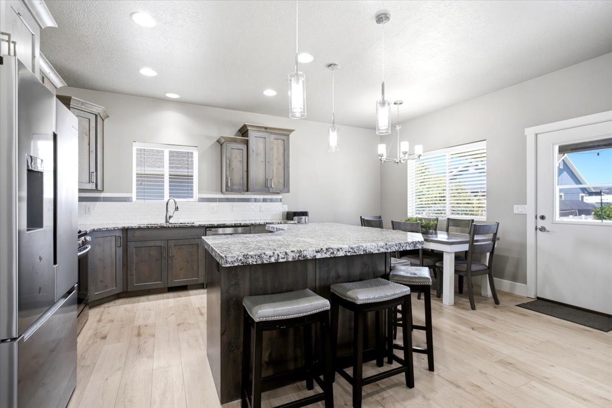 Contemporary kitchen featuring wood-finish flooring, recessed lighting, and a kitchen island with stone countertops