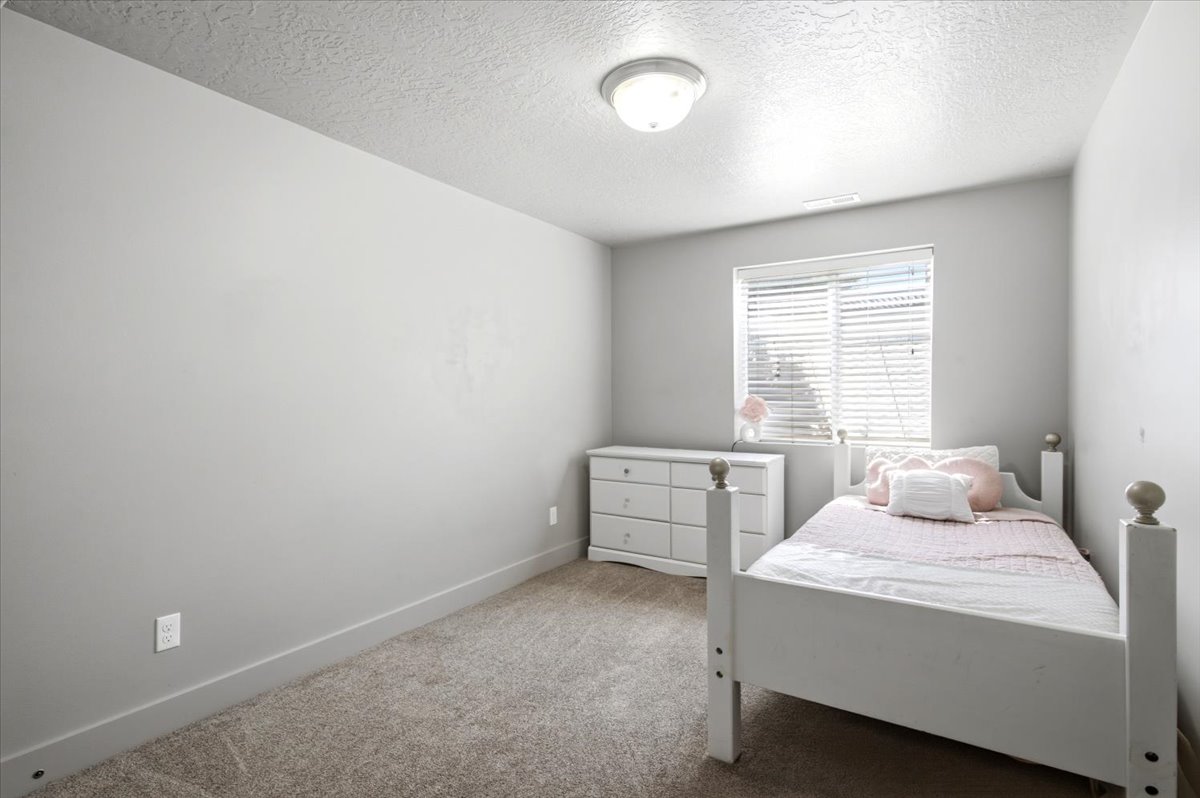 Neutral-toned room featuring a single window with horizontal blinds, providing natural light