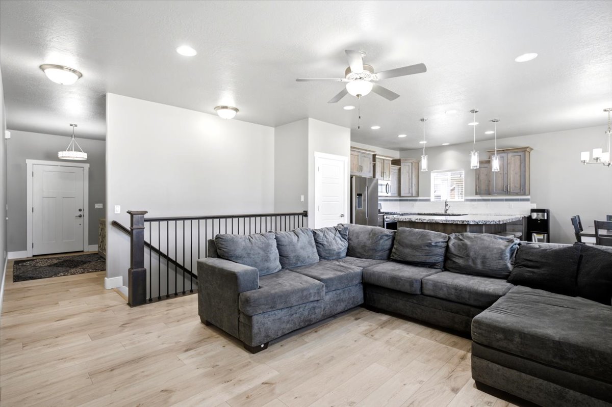 Open-concept living area featuring light wood-finish flooring, recessed lighting, and a contemporary ceiling fan