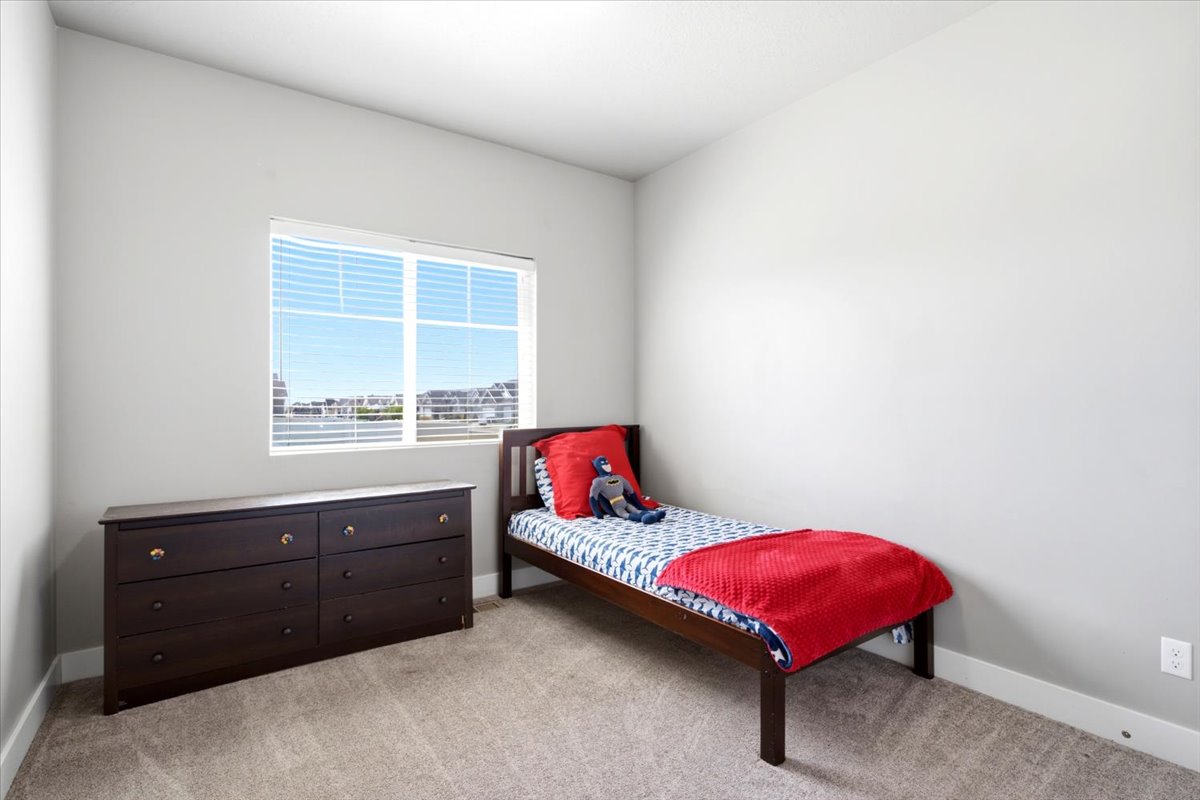Bright room featuring a large window, neutral wall paint, and light-toned carpet flooring
