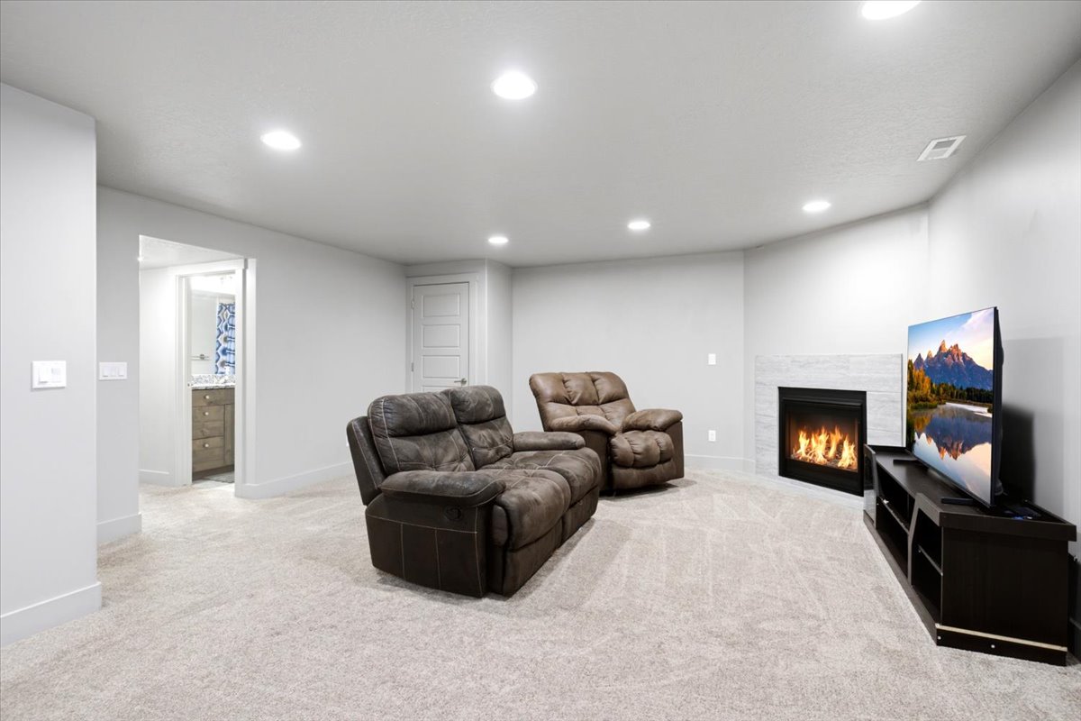 Carpeted interior space featuring a corner fireplace with a tiled surround