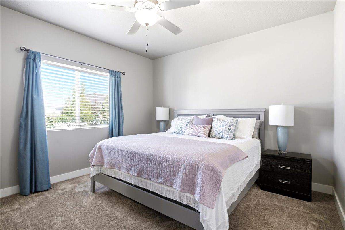 Carpeted room featuring a ceiling fan, a window with horizontal blinds, and a built-in headboard