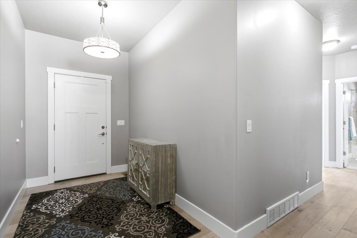 Entryway featuring light wood-finish flooring, crisp white baseboards, and neutral wall tones