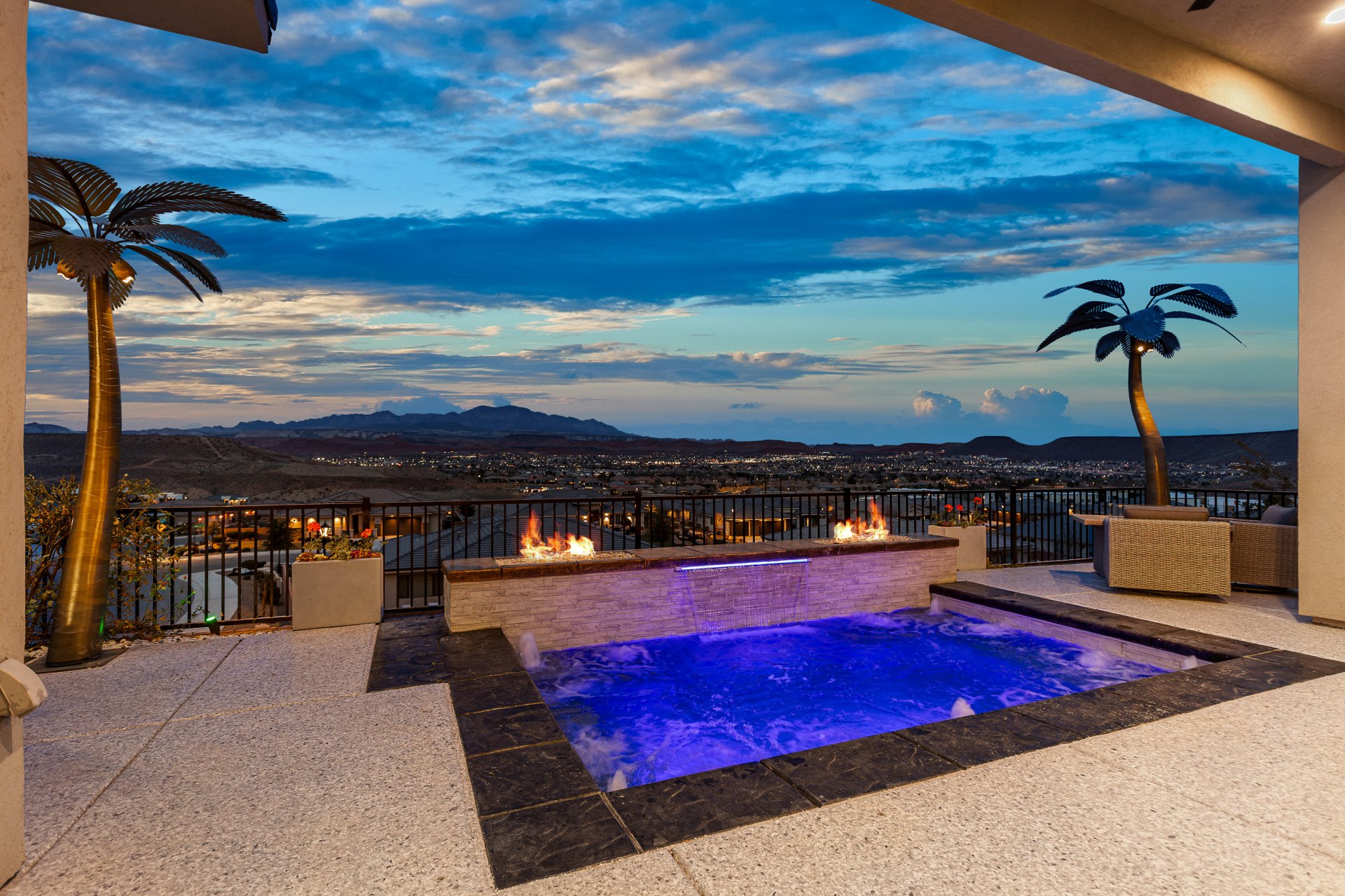 Outdoor spa with blue lighting, stone-tiled fire feature, and expansive mountain scenery