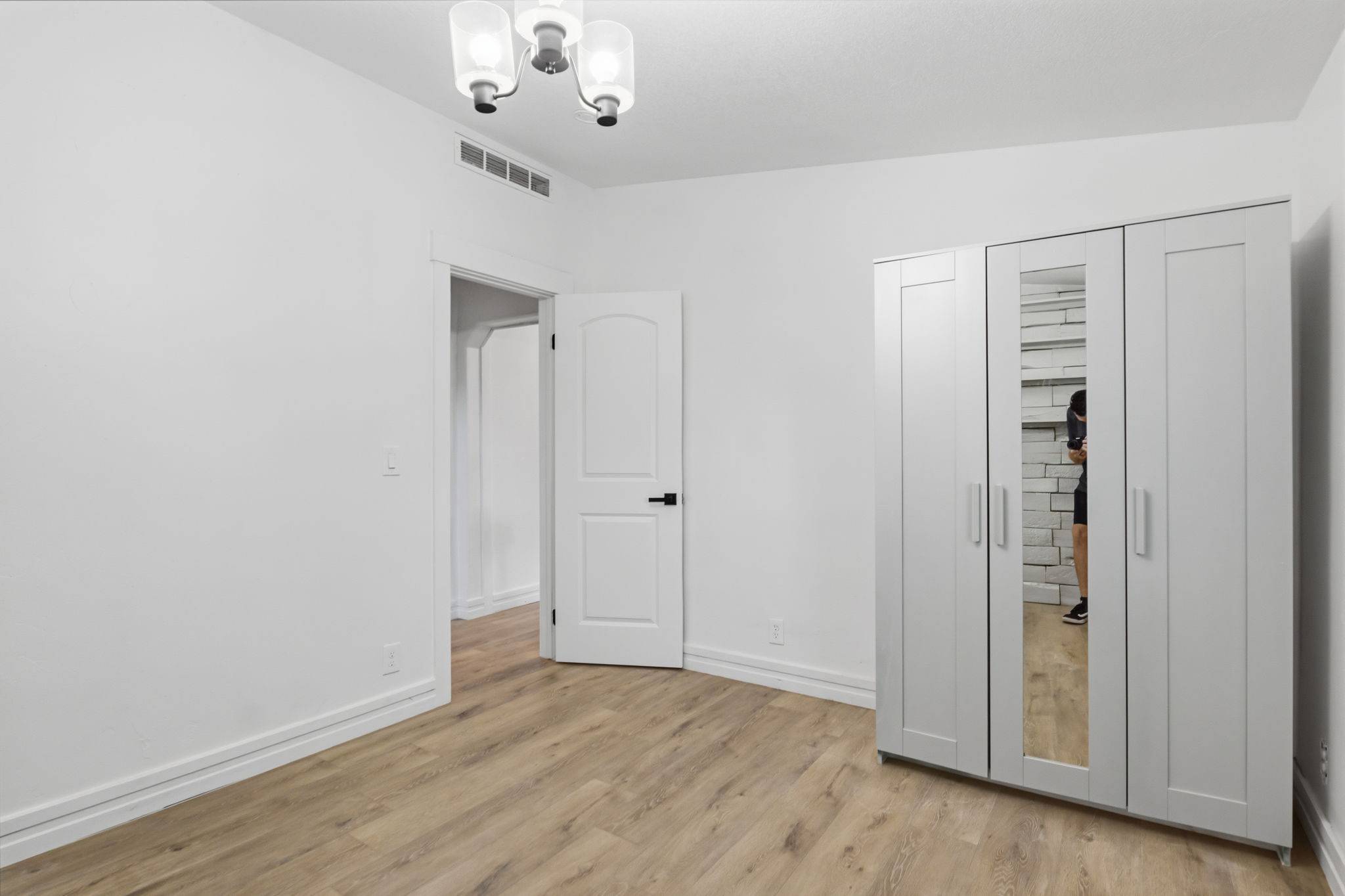 Room featuring light wood-finish flooring, white walls, and a modern ceiling light fixture