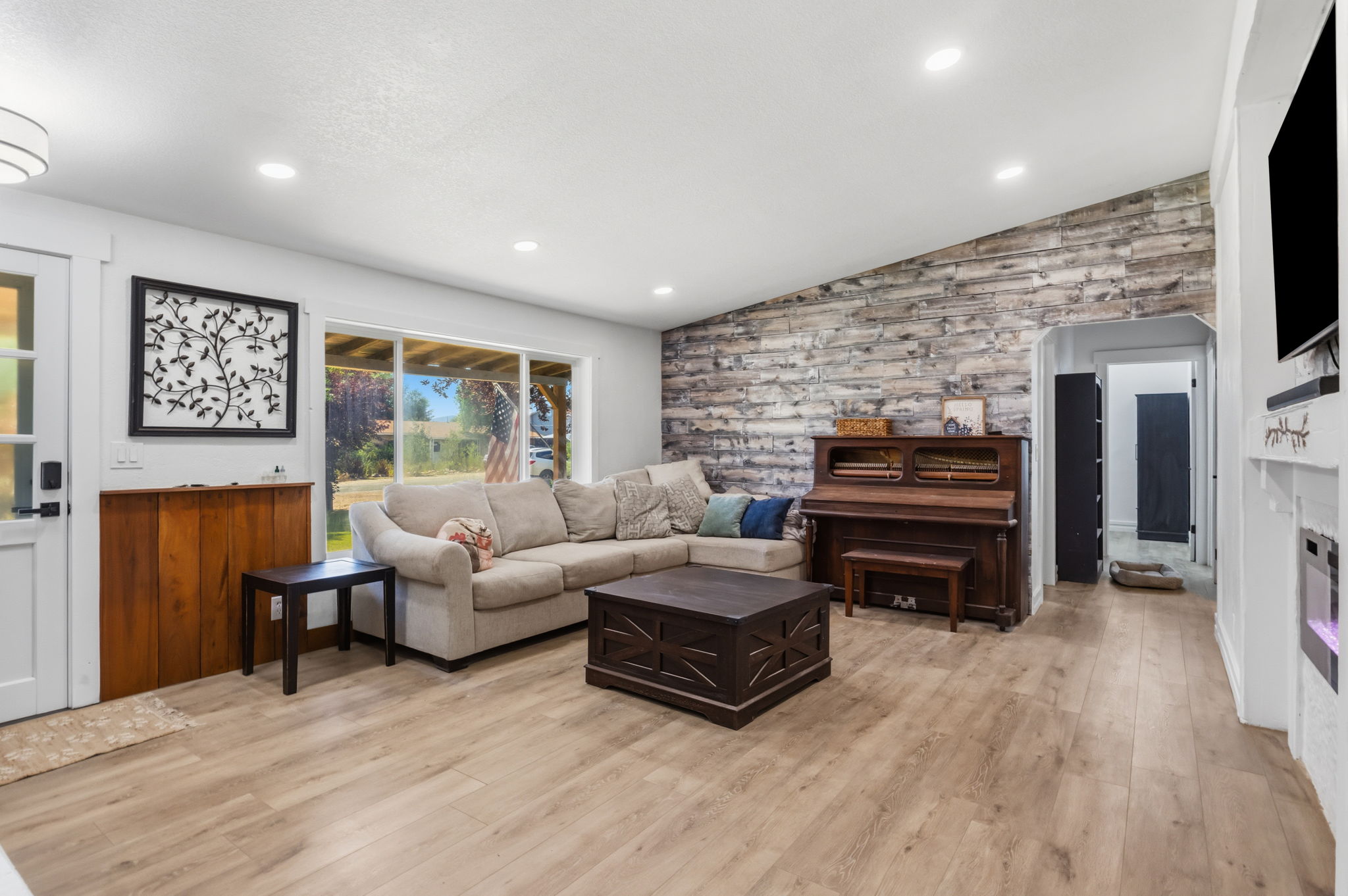 Spacious living area featuring wood-finish flooring, a textured accent wall, and recessed lighting
