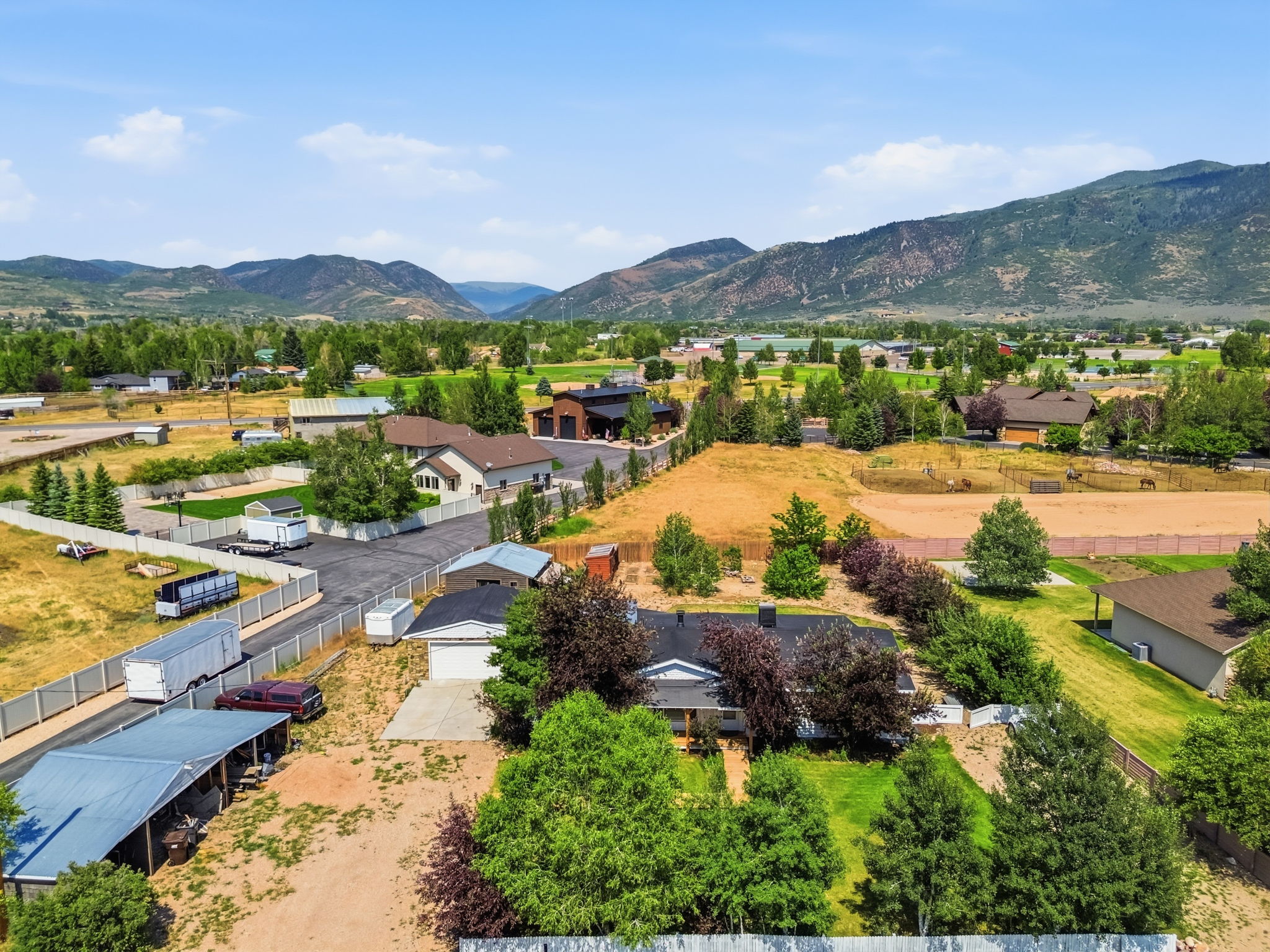 Ranch-style residence featuring a prominent front porch, an attached garage, and mature landscaping