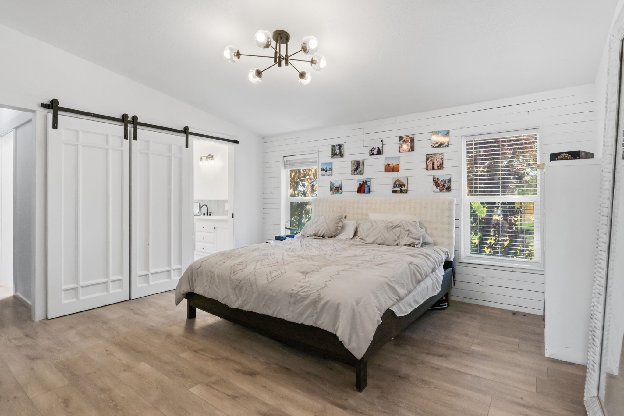 Spacious room featuring wood-finish flooring, a modern sputnik chandelier, and a white shiplap accent wall