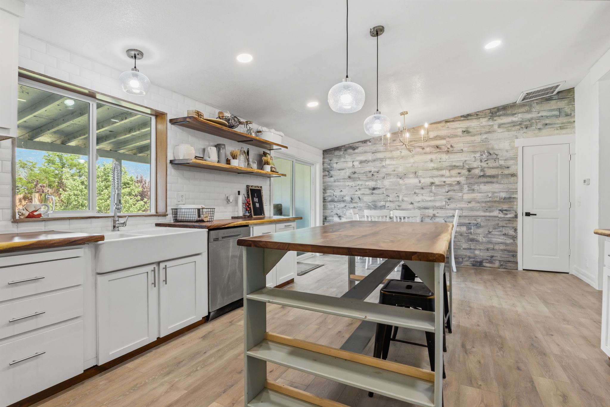 Kitchen featuring light wood-finish flooring, white cabinetry with silver hardware, and a white farmhouse sink