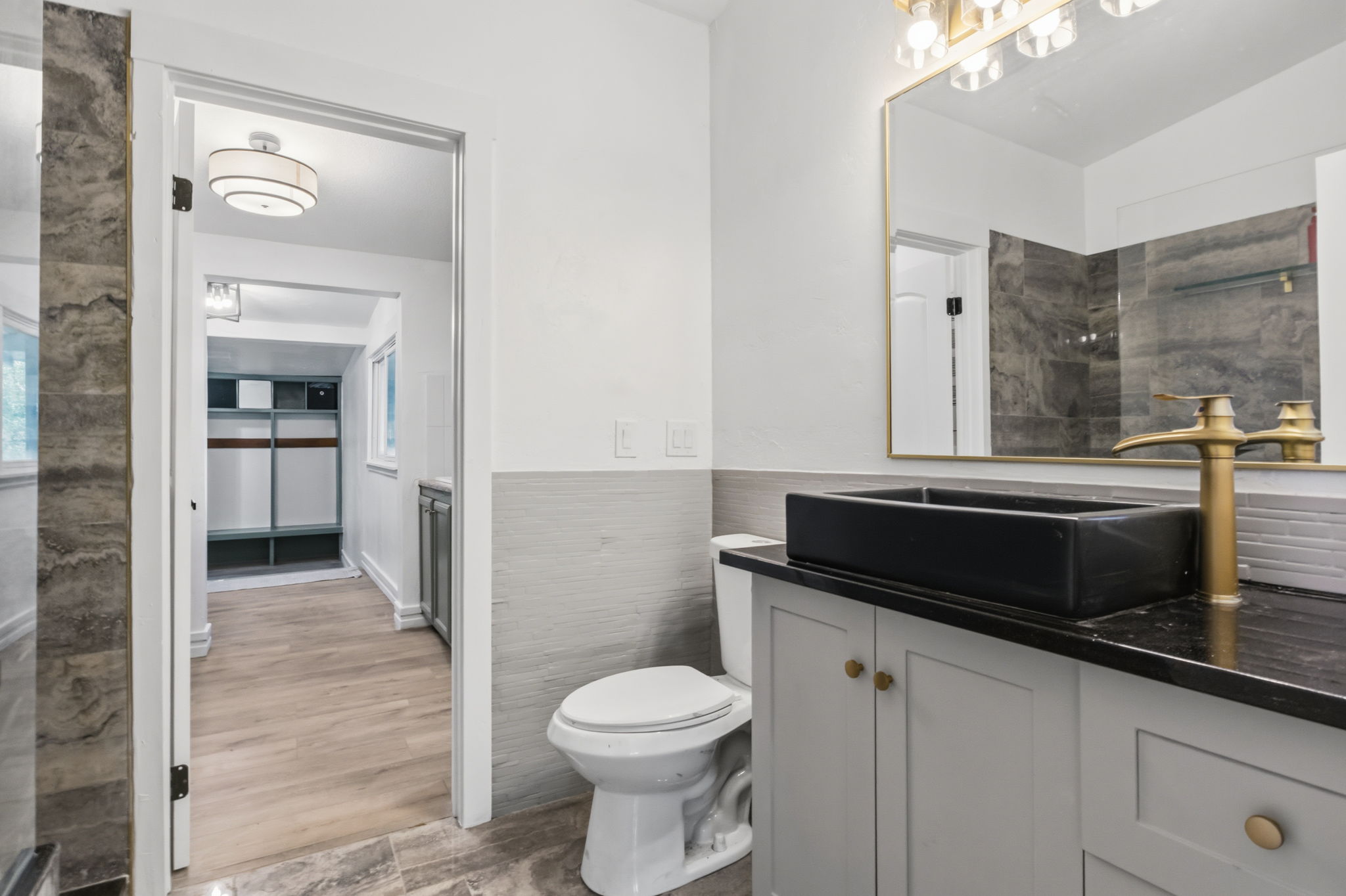 Bathroom featuring a vessel sink, gold-finish faucet, and coordinating vanity with gold-tone hardware