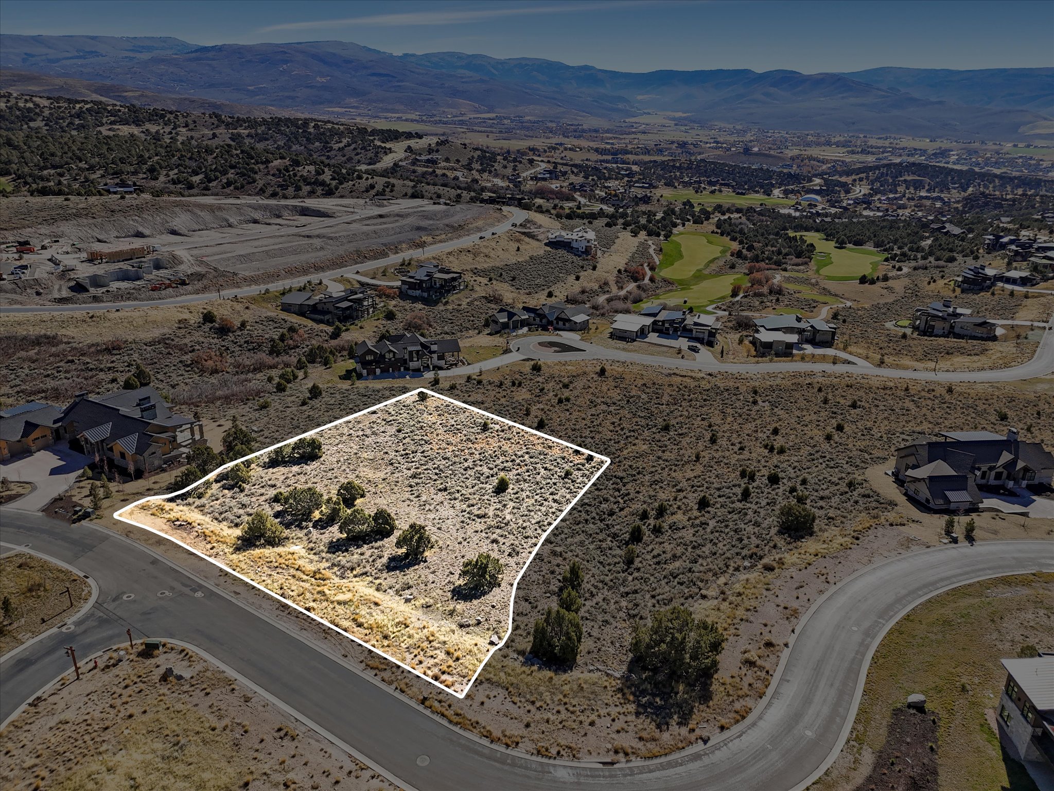 Expansive building lot with visible boundary lines, situated in a developed neighborhood