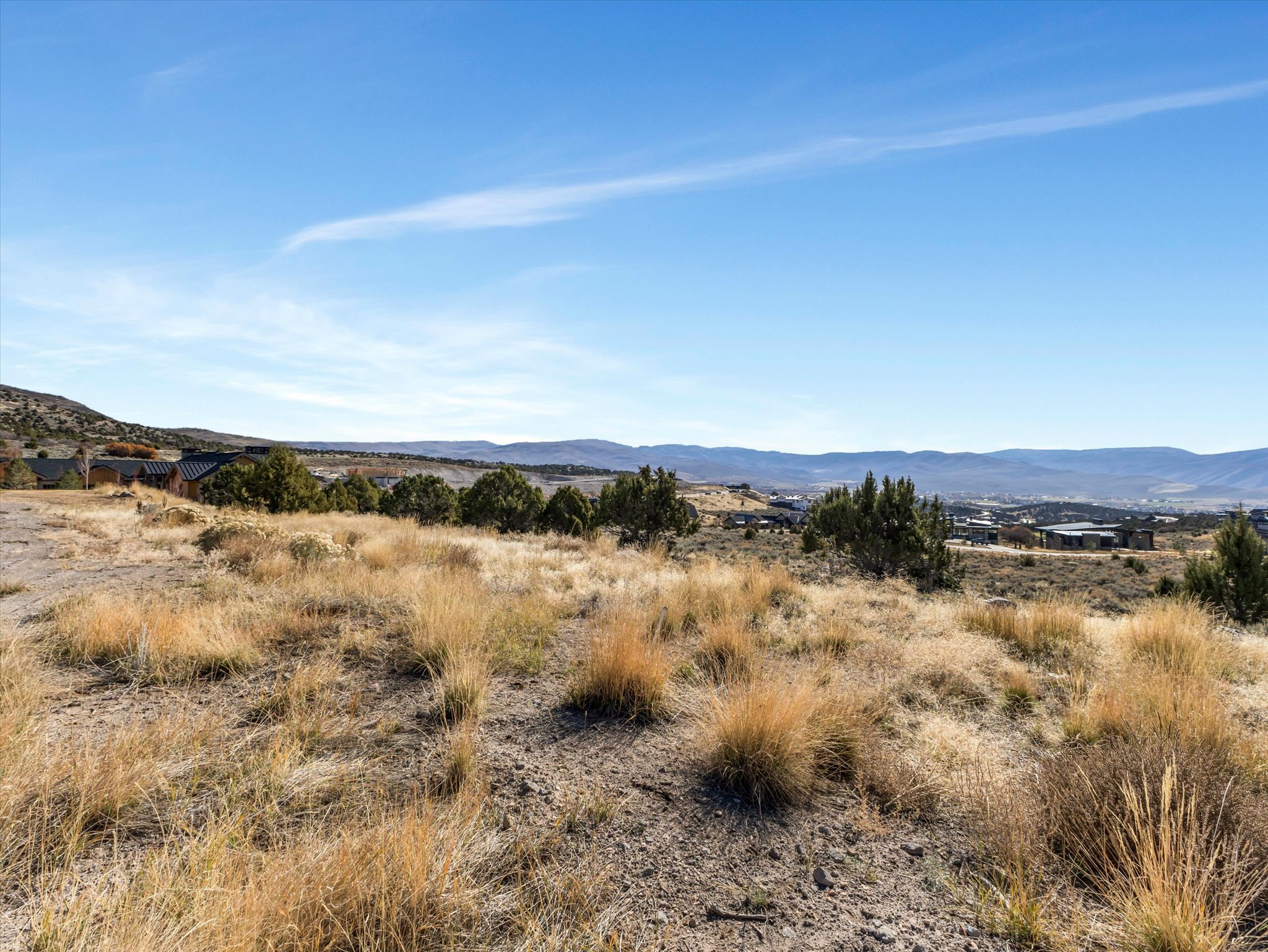 Expansive hillside property featuring natural vegetation and distant mountain ranges