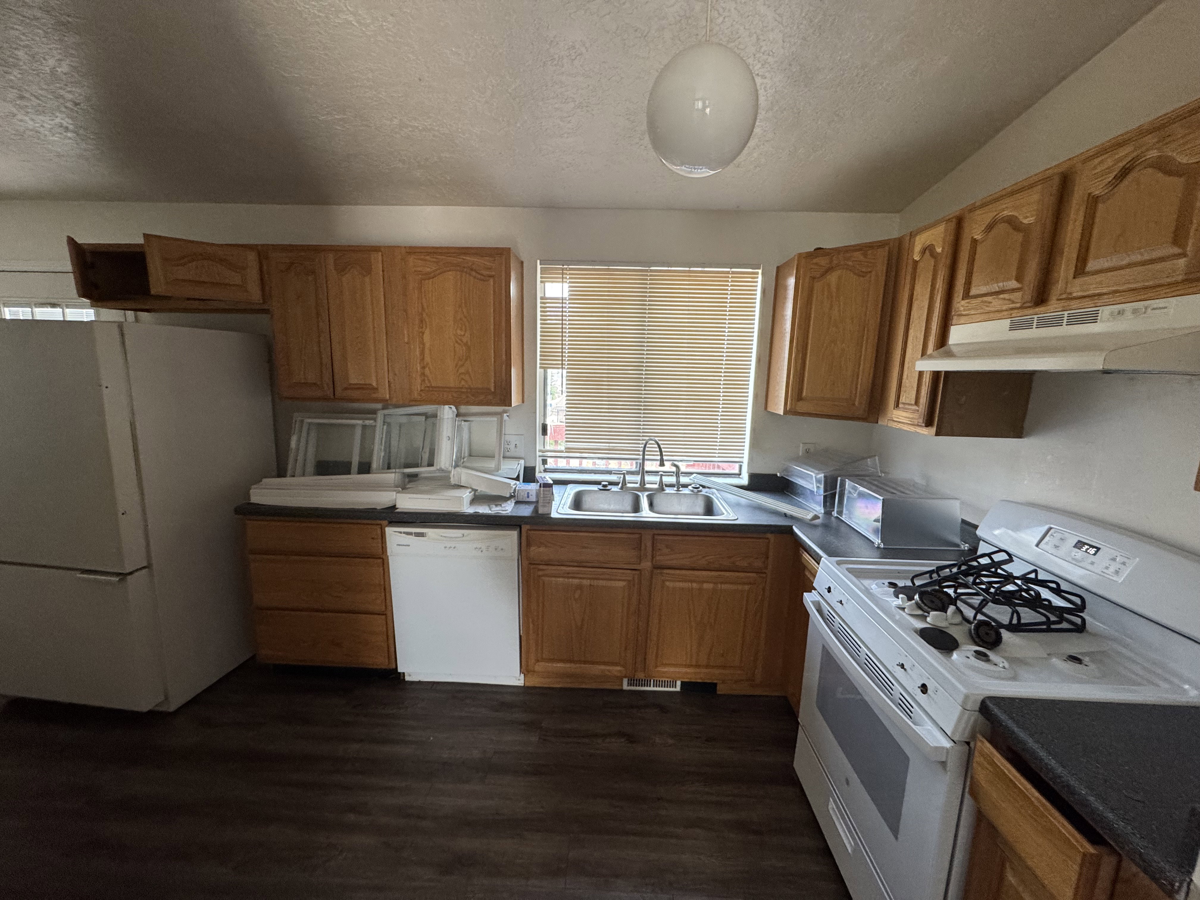 Kitchen featuring wood-finish cabinetry, dark countertops, and wood-finish flooring