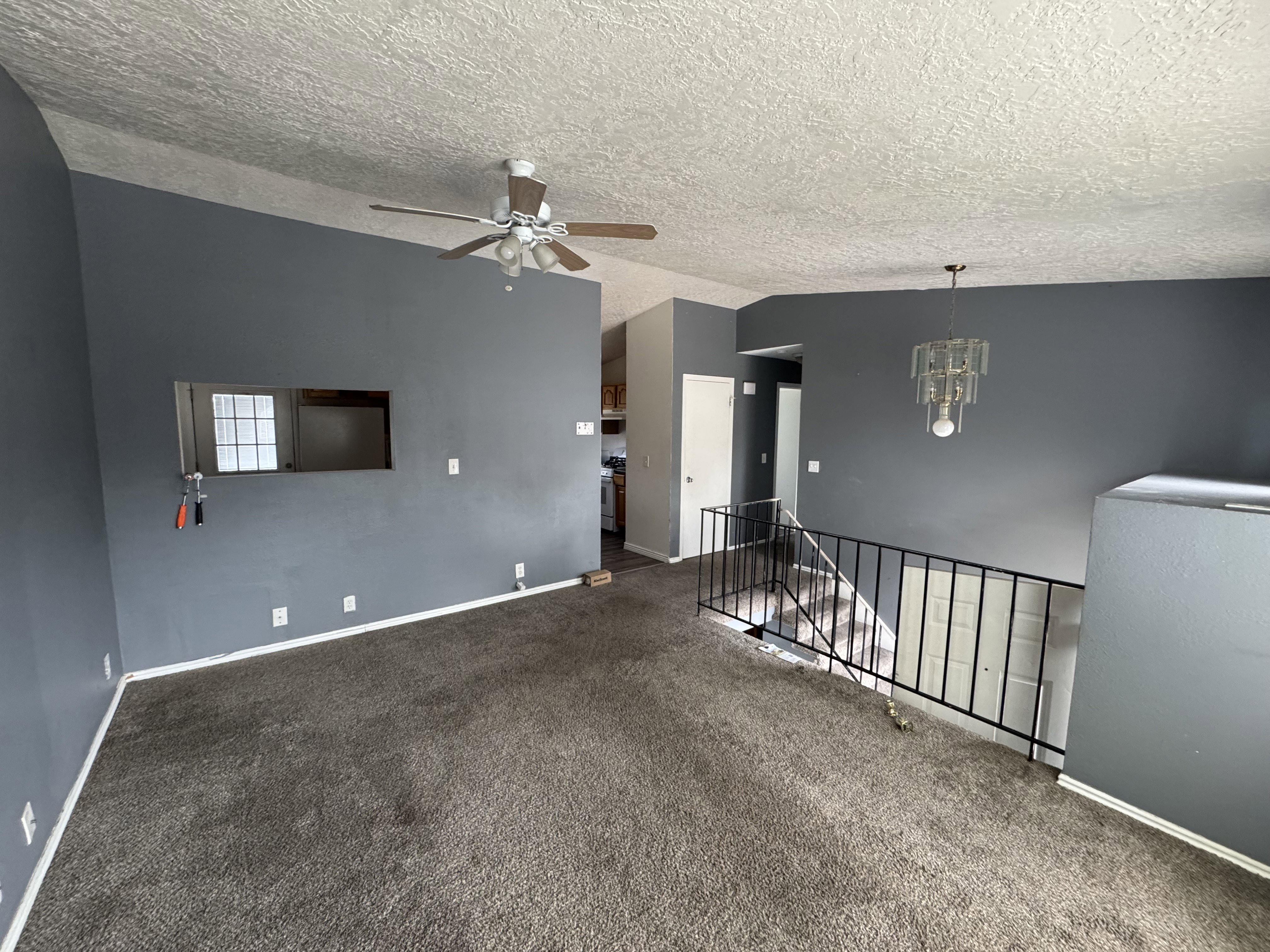 Carpeted living area with dark gray walls and a textured ceiling