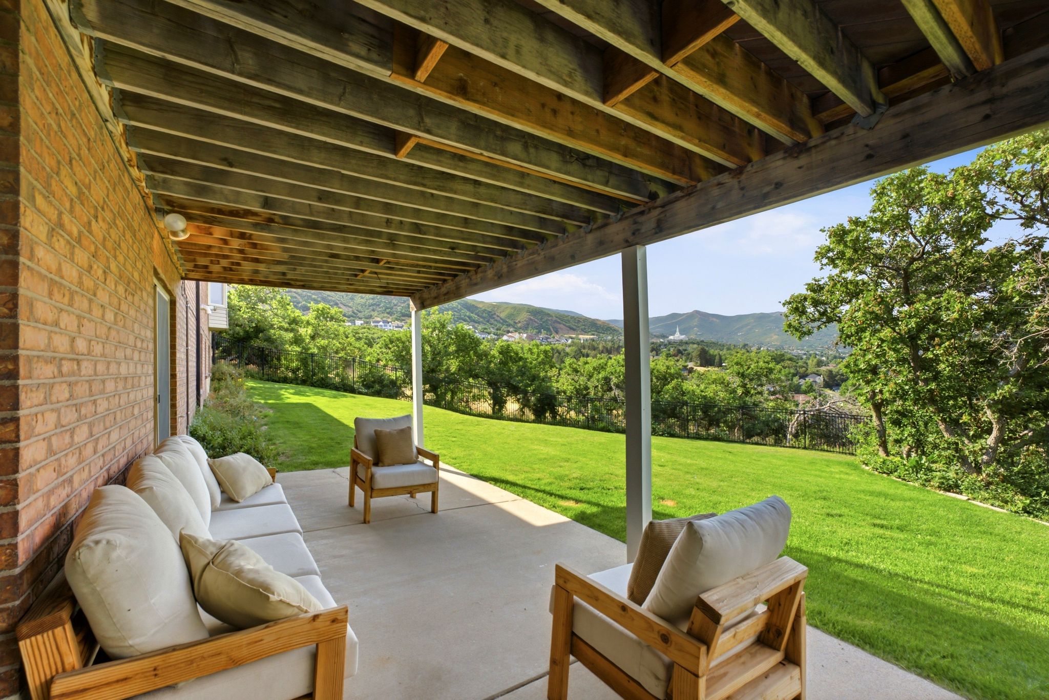 Covered patio featuring an exposed wood beam ceiling, concrete flooring, and a brick exterior wall