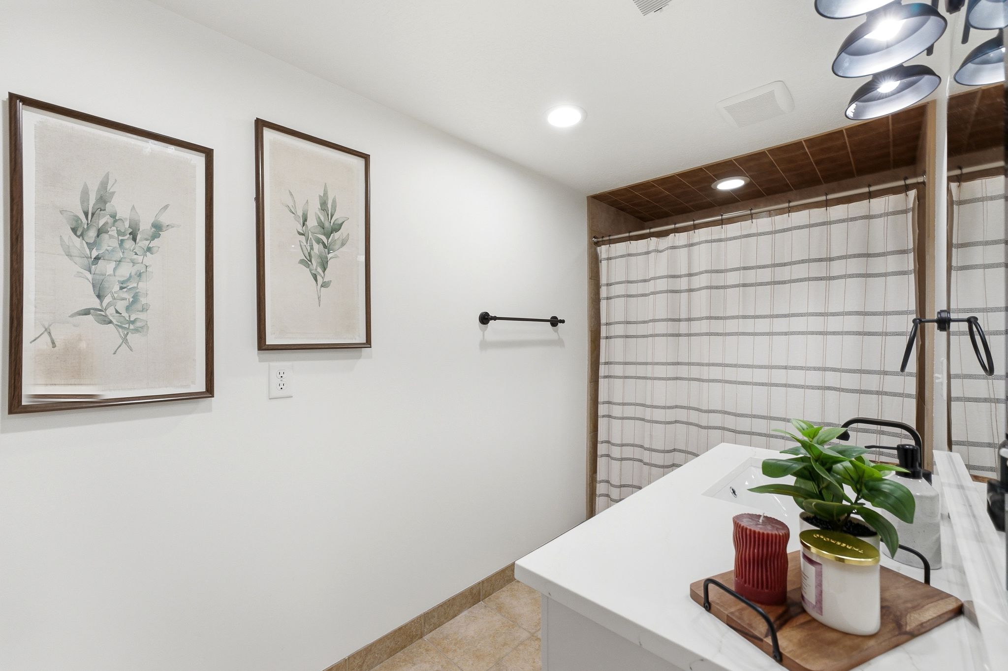 Bathroom featuring a white vanity with an integrated sink, black faucet, and a shower with a striped curtain