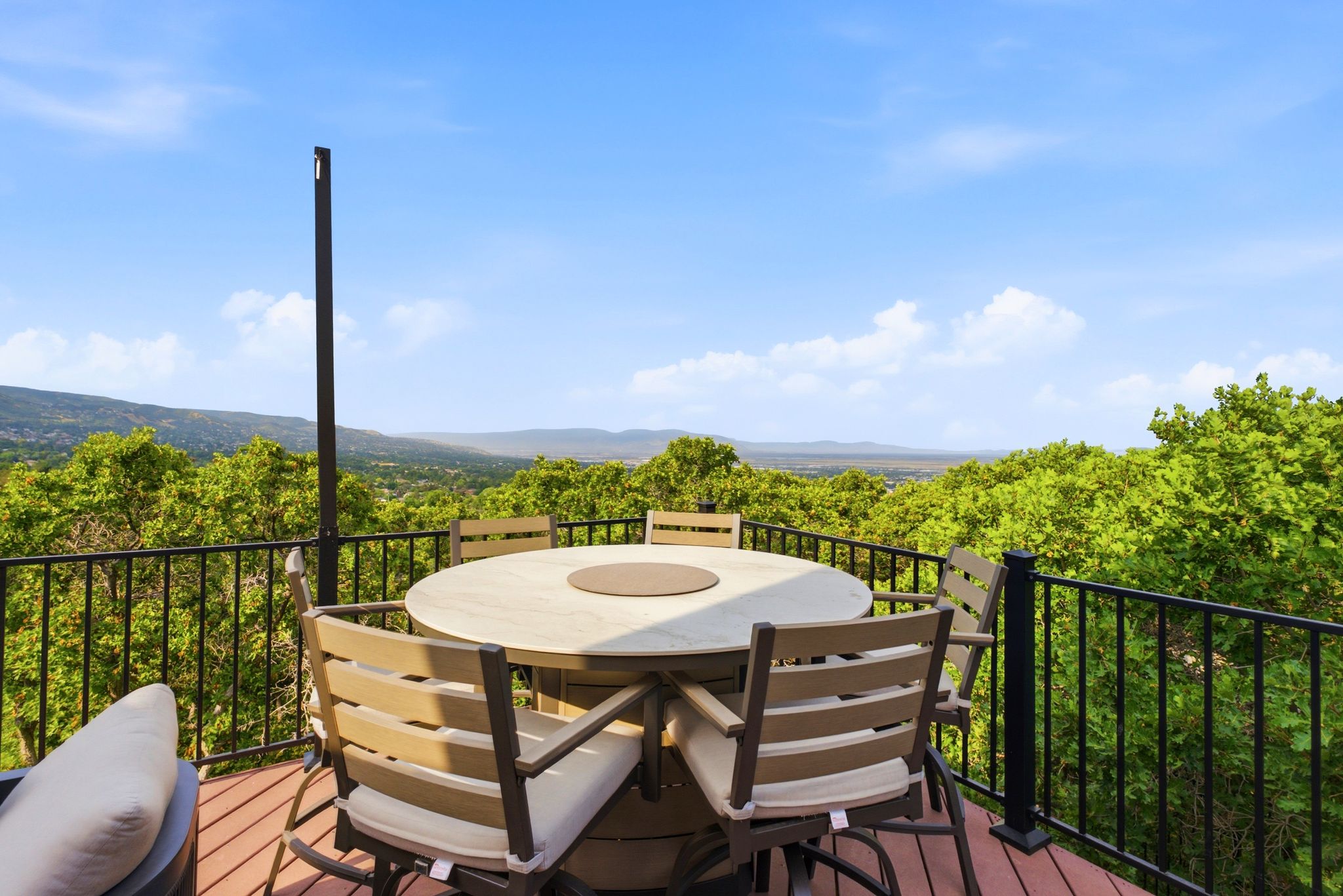 Expansive outdoor deck with composite decking, black metal railing, and panoramic mountain scenery