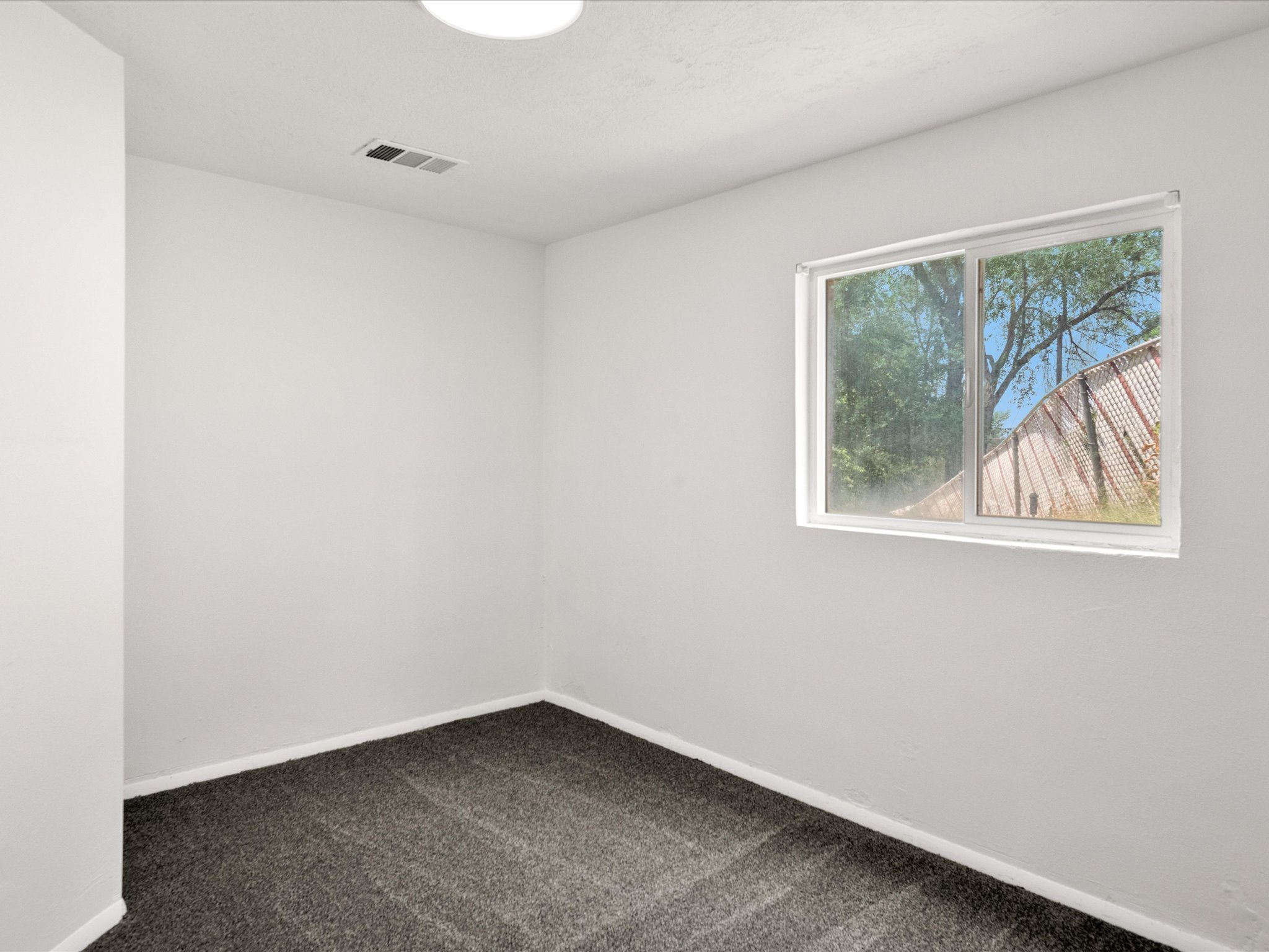 Room featuring neutral wall tones, dark grey carpeting, and white baseboards