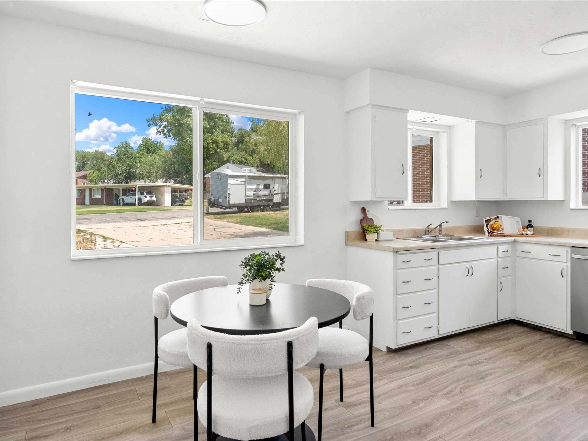 Bright kitchen with light wood-finish flooring, white cabinetry, and light countertops