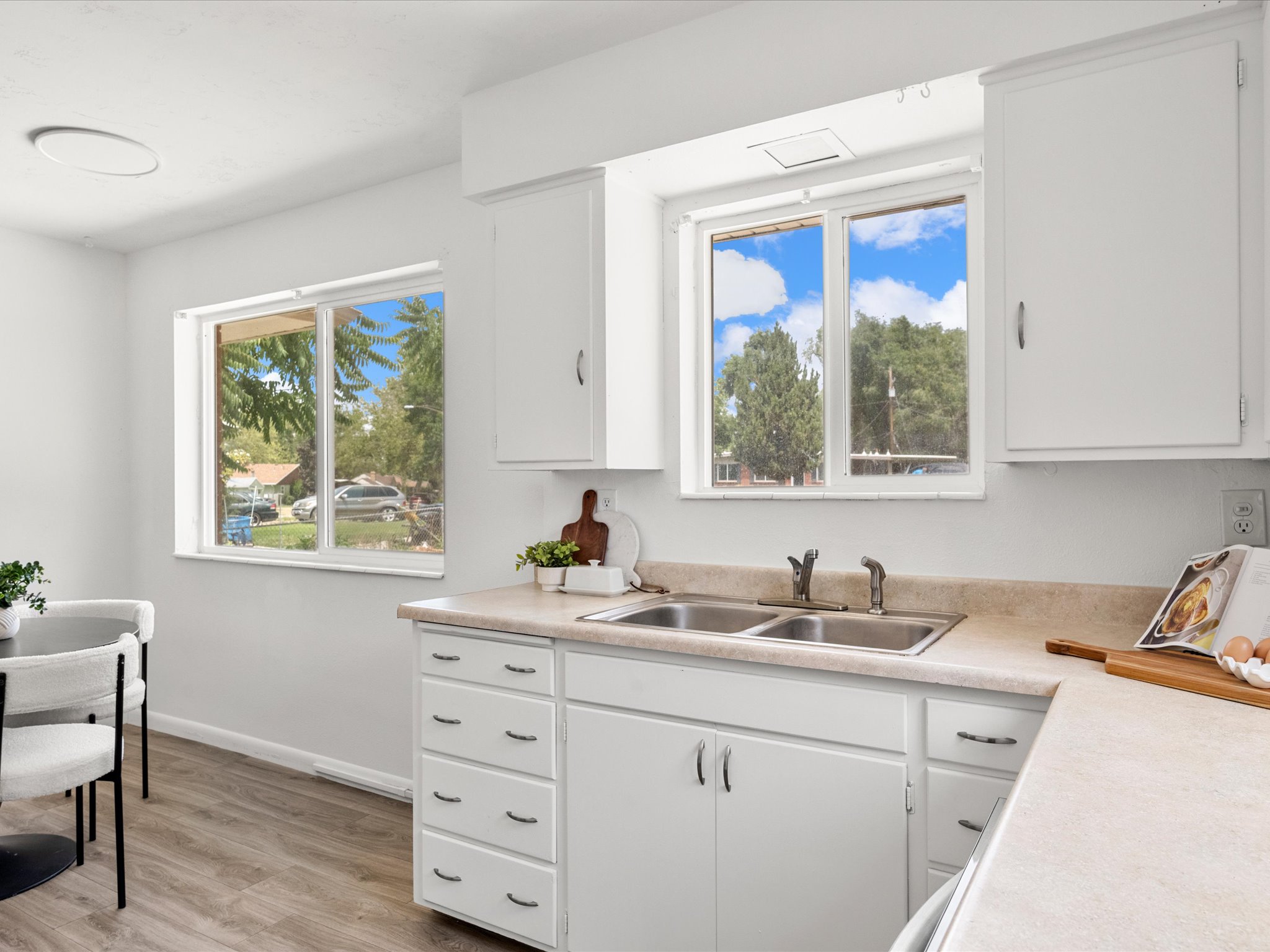 Kitchen featuring white cabinetry, light-toned countertops, and a double basin sink with a chrome faucet