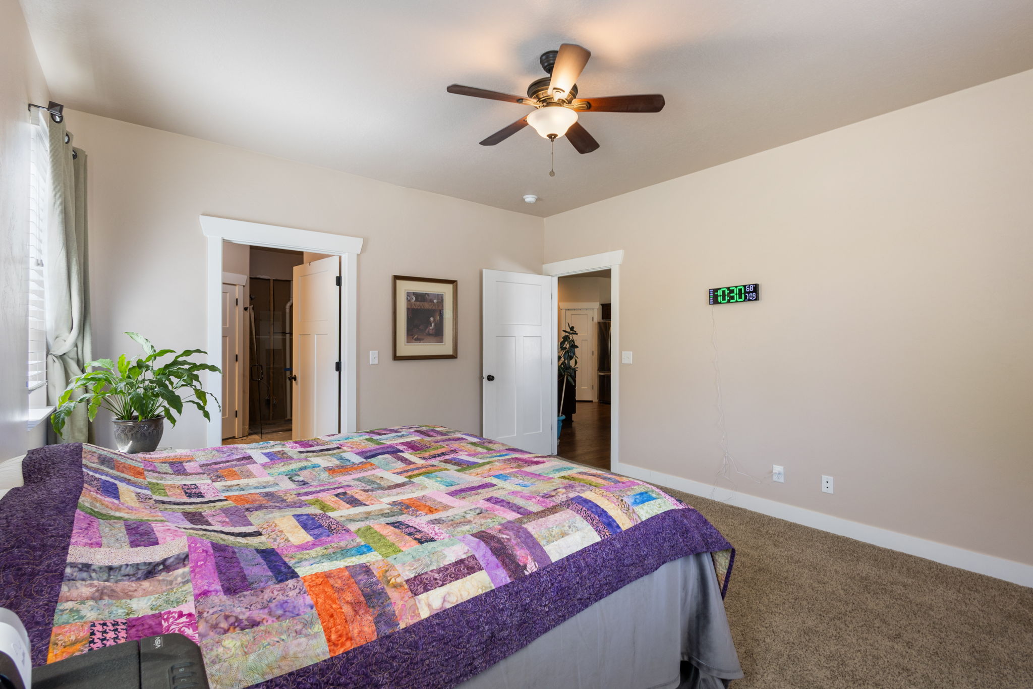 Carpeted bedroom with neutral wall tones and a ceiling fan with light fixture