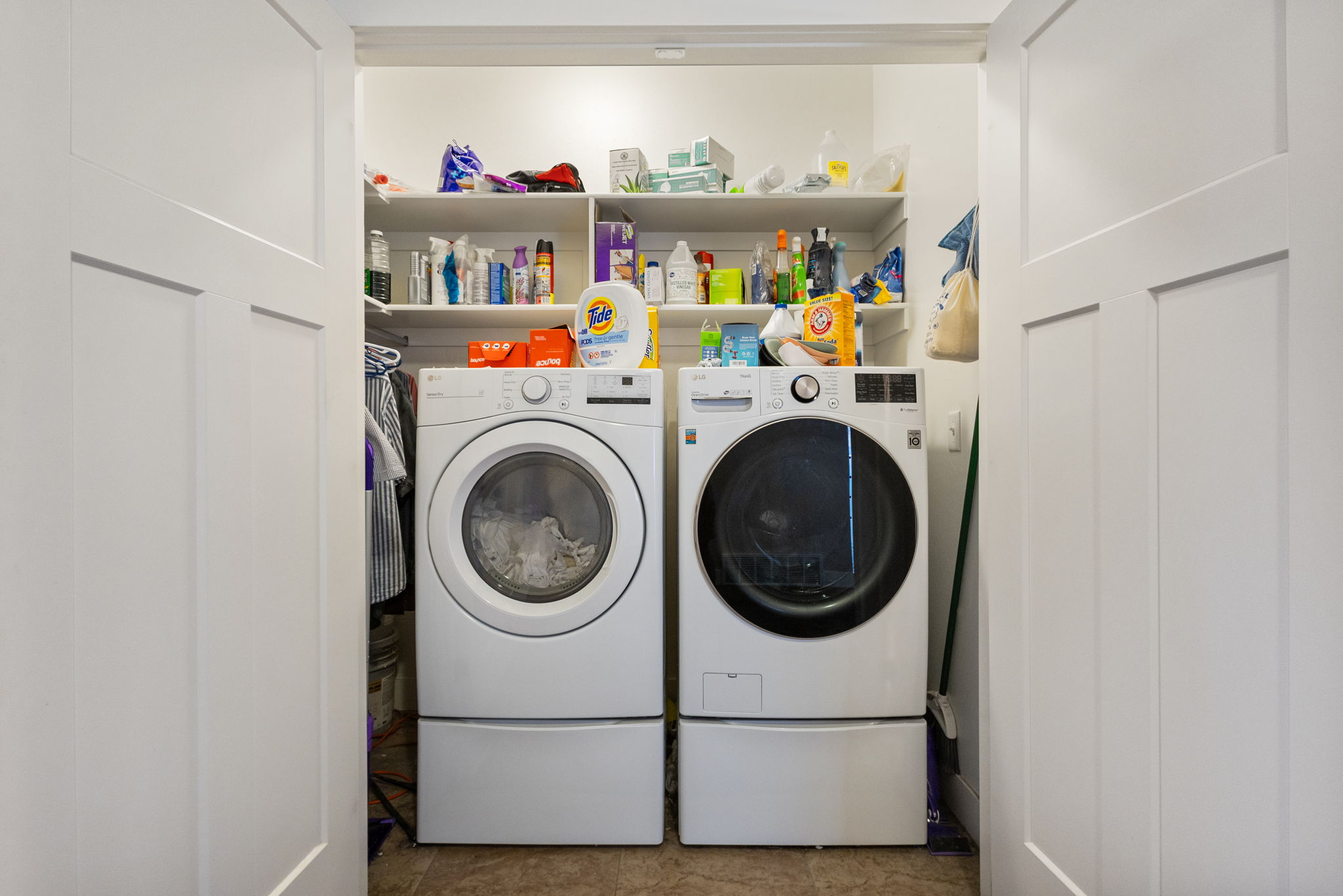 Laundry area featuring a side-by-side washer and dryer, integrated shelving, and white panel doors