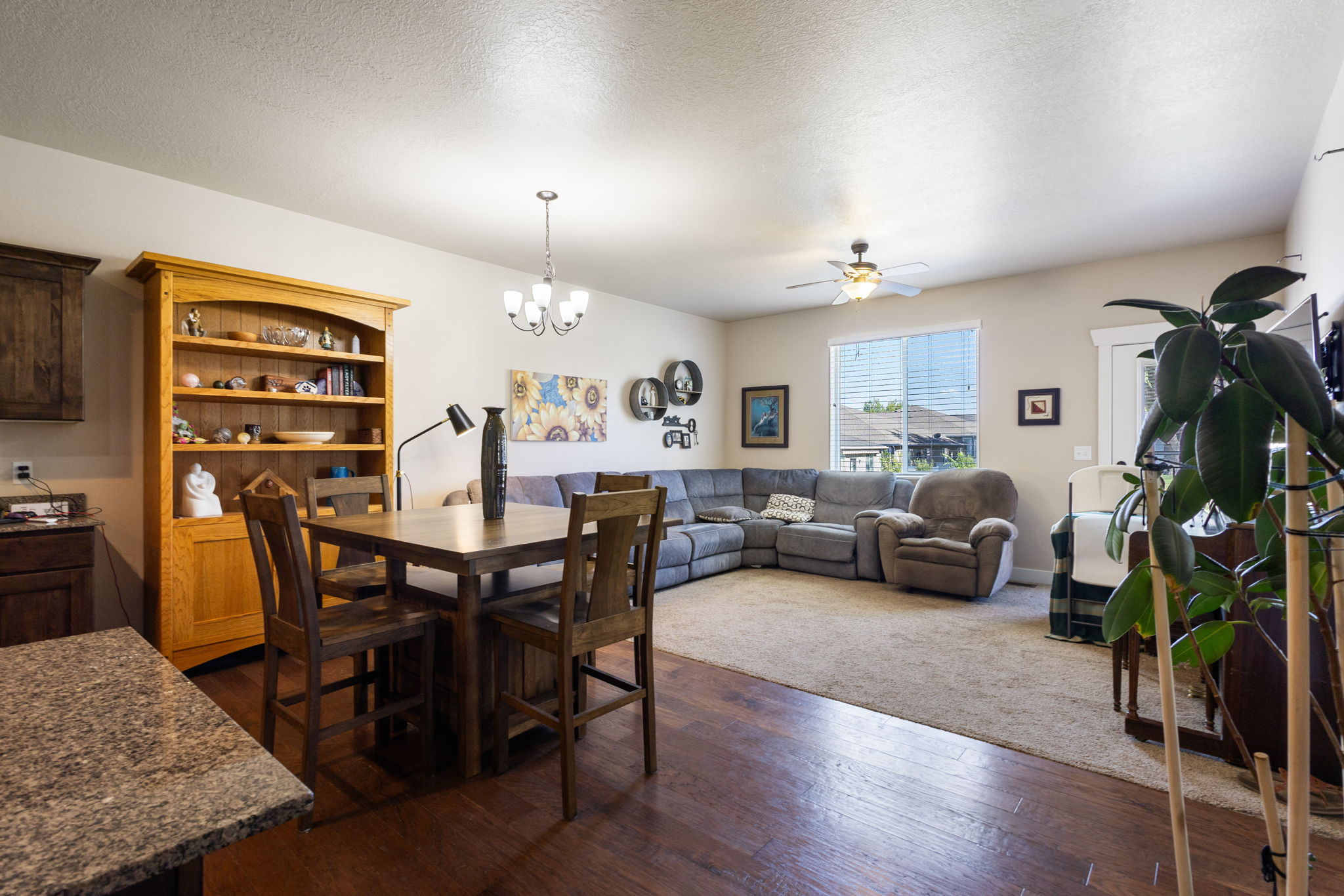 Open-concept living space featuring wood-finish flooring extending into the kitchen and dining areas