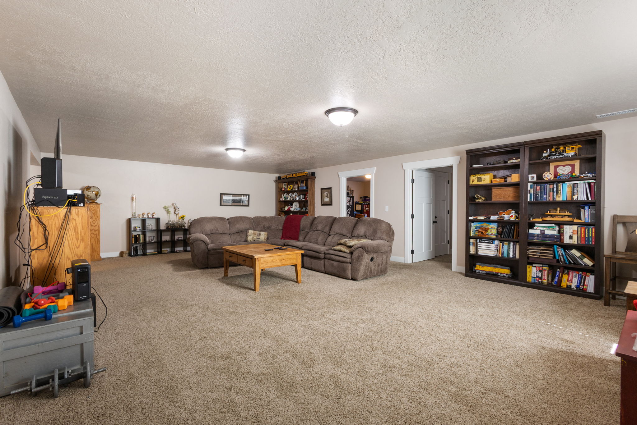 Spacious carpeted room featuring recessed lighting and a built-in dark wood bookcase