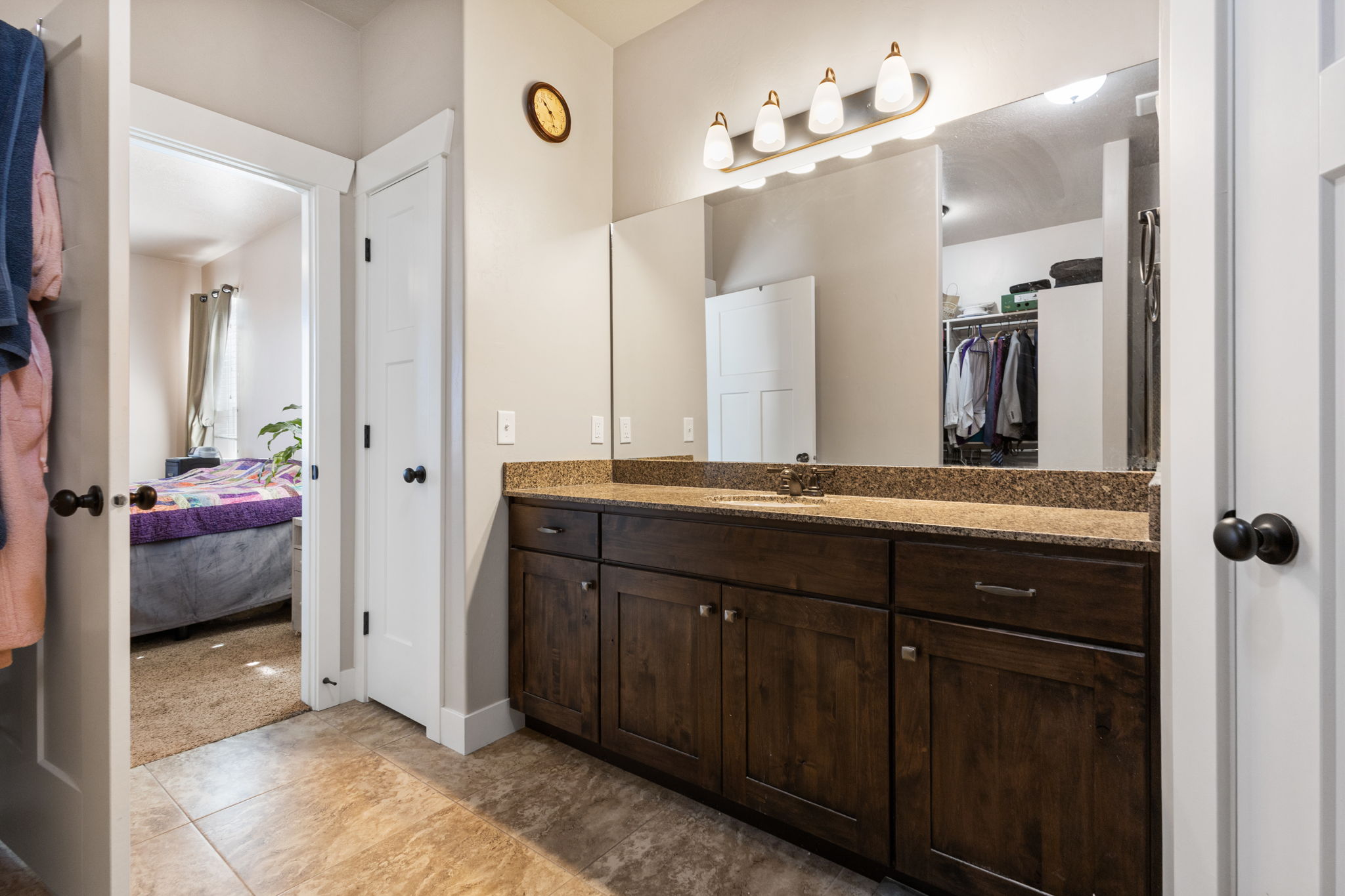 Bathroom vanity featuring dual sinks, a granite-look countertop, and dark wood-finish cabinetry