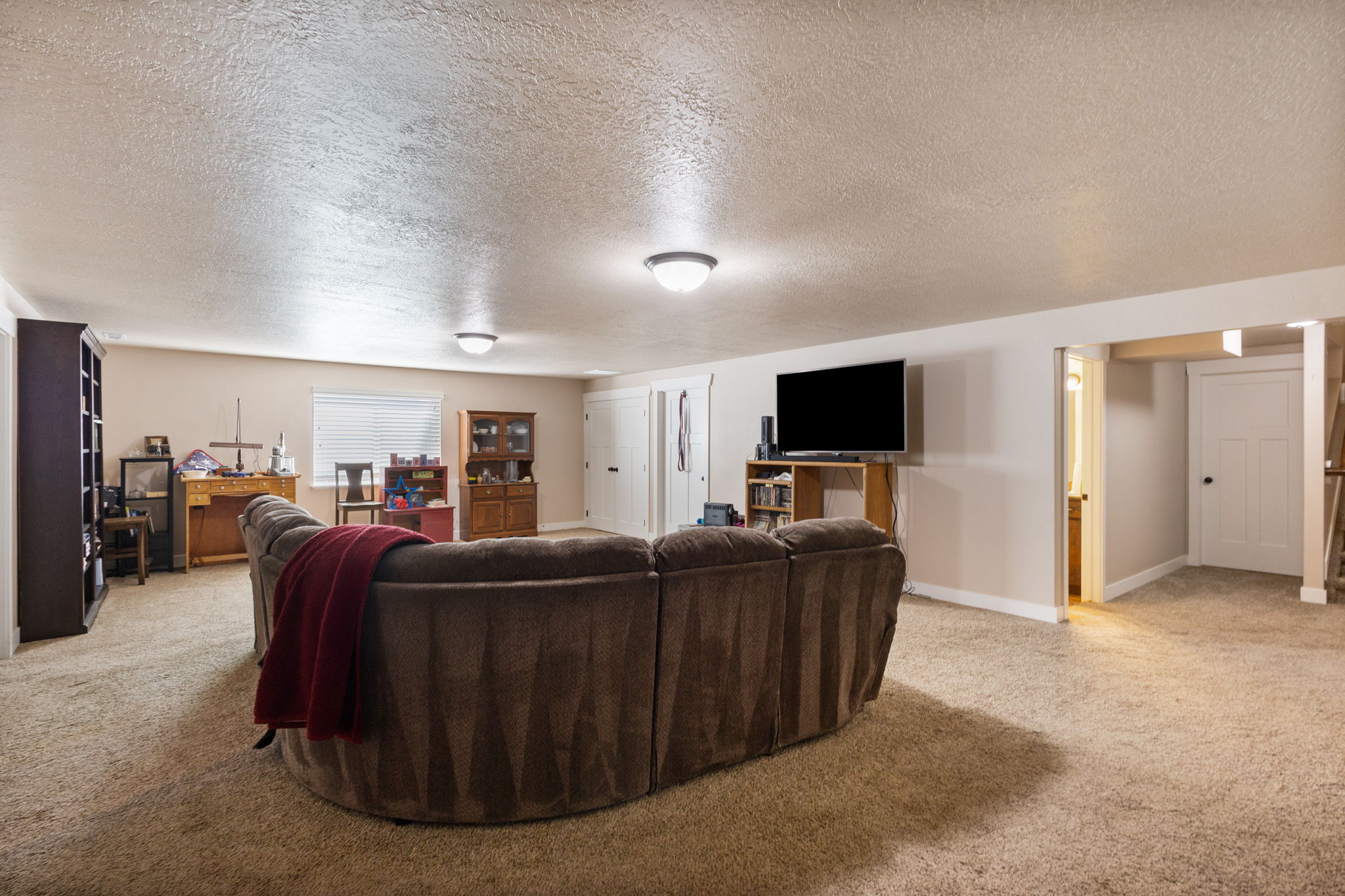 Spacious lower-level room featuring neutral wall tones, carpet flooring, and recessed ceiling lighting