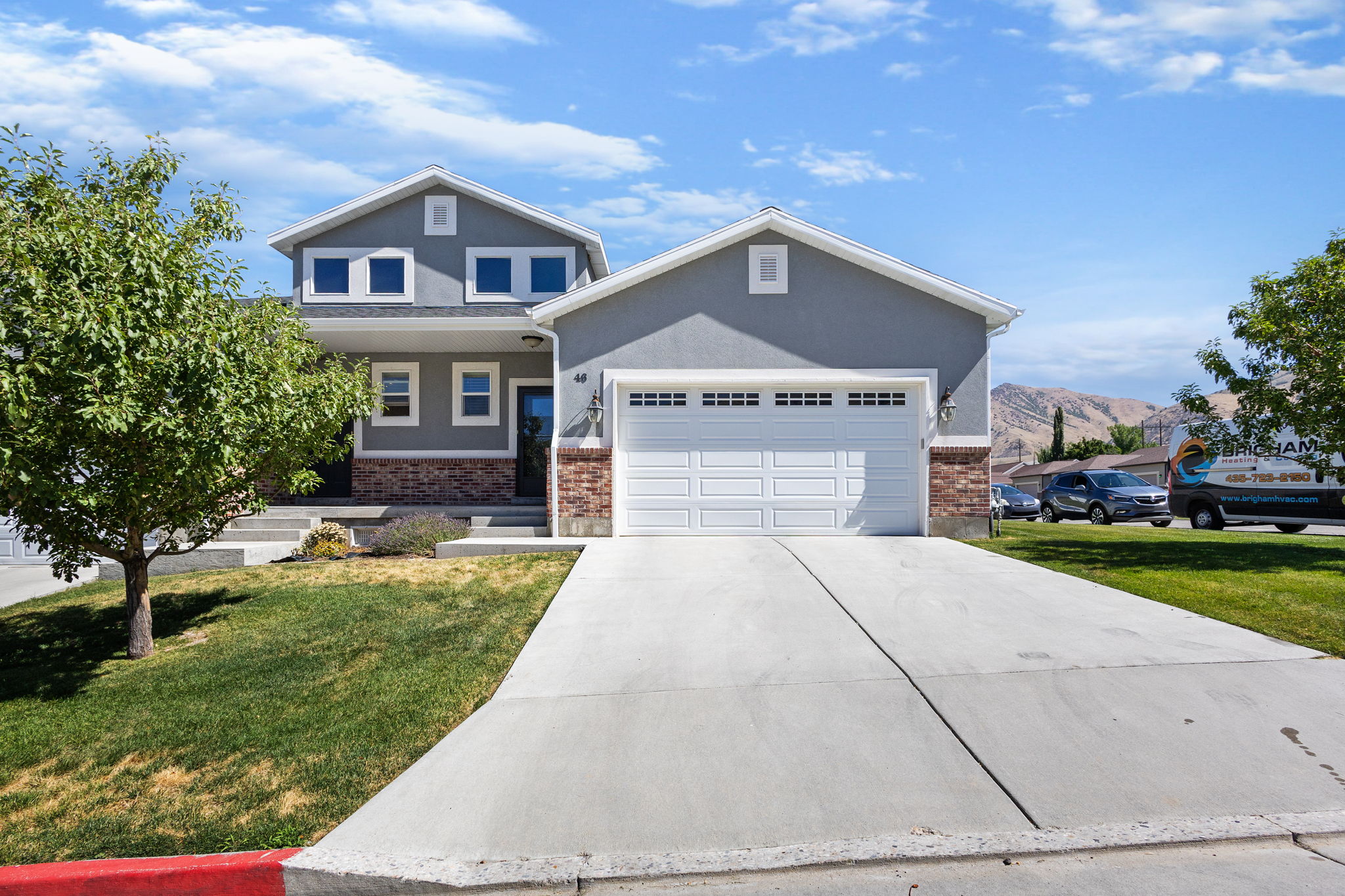 Contemporary exterior featuring a two-car garage, concrete driveway, and established landscaping